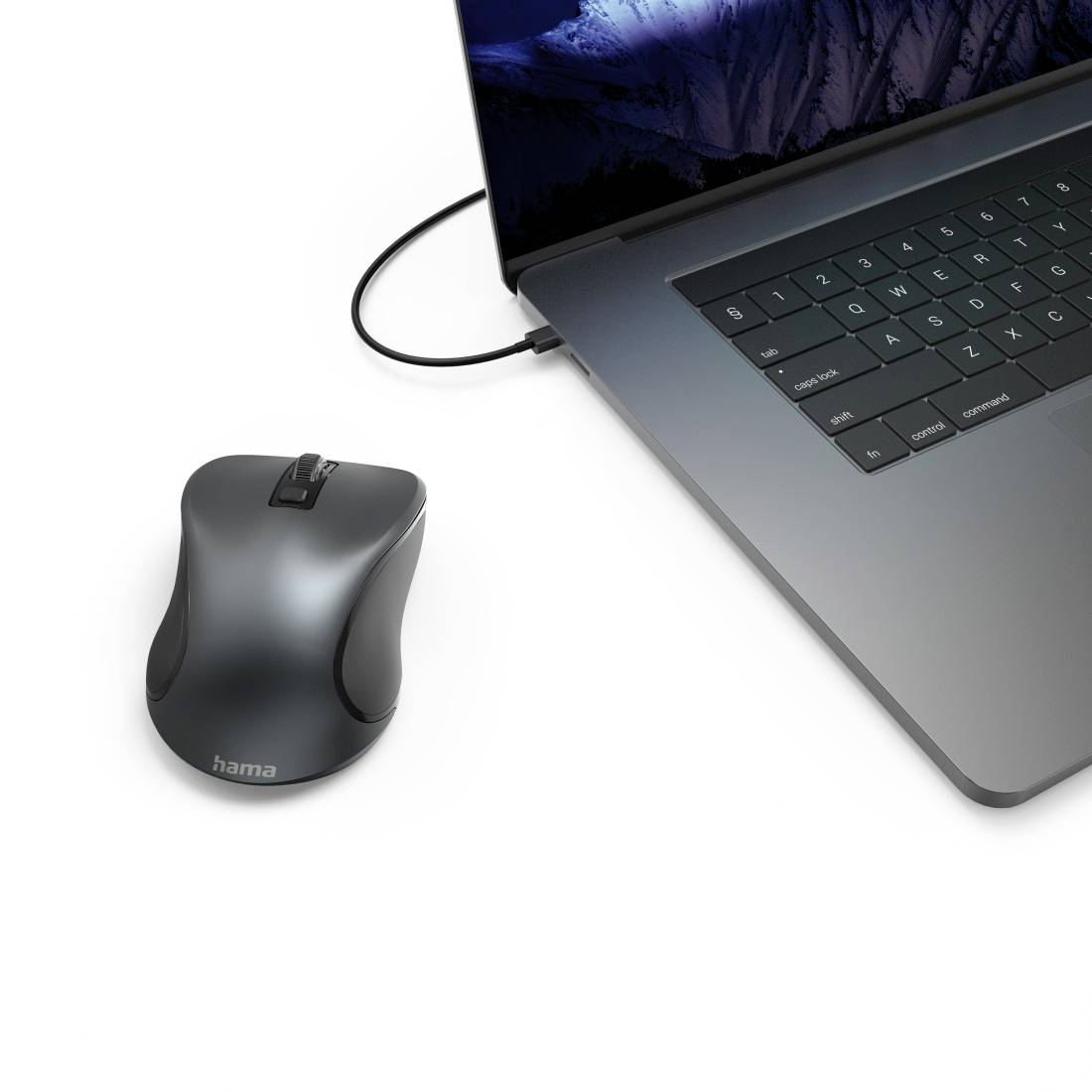 Notebook s tmavým tělem na stole; vedle bezdrátová počítačová myš. Na obrazovce je horská krajina.