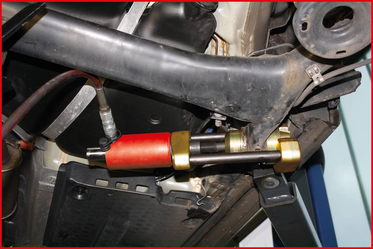 Mechanická část zavěšení vozidla s hydraulickým tlumičem, propojená s ramenem, které podporuje vozidlový podvozek.
