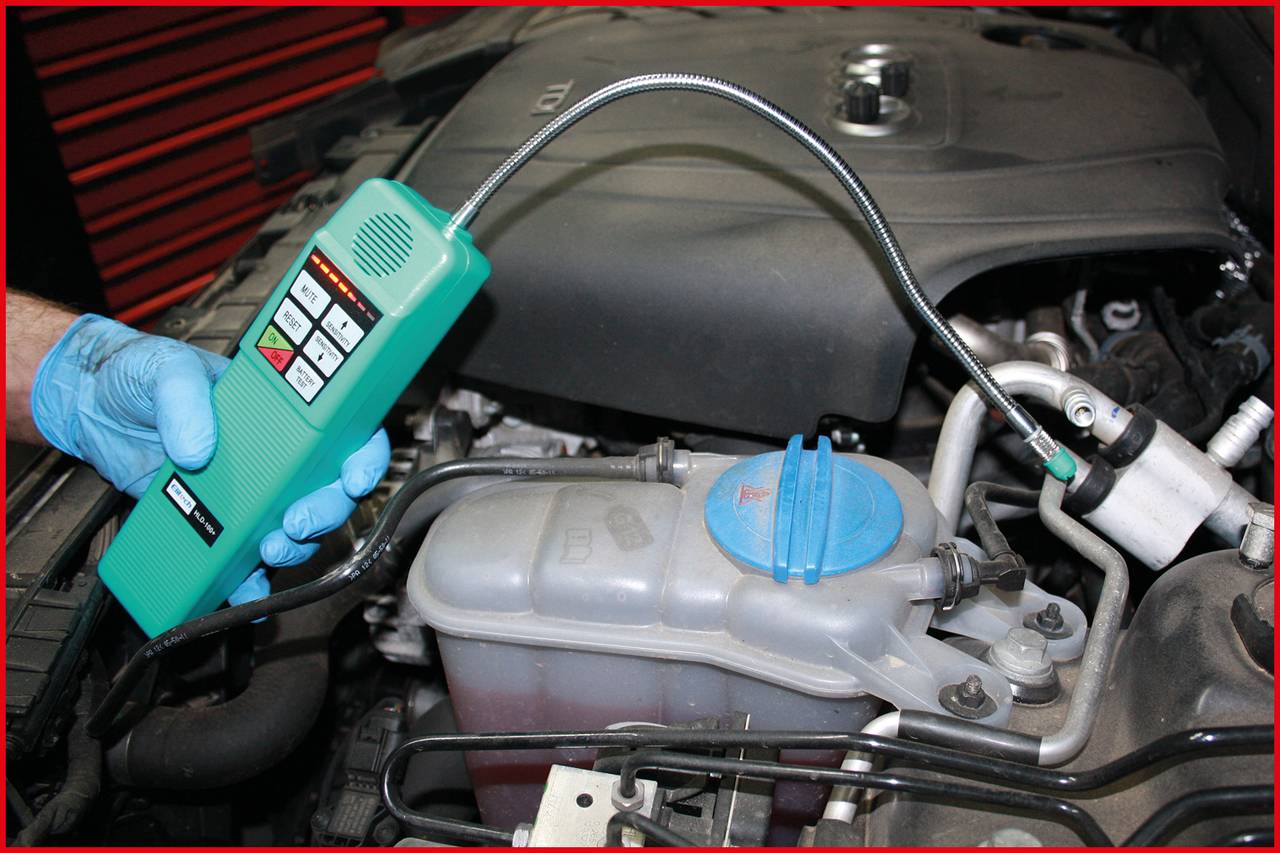 Mechanik testuje nádobku brzdové kapaliny automobilu diagnostickým přístrojem. Auto stojí v autoservisu.