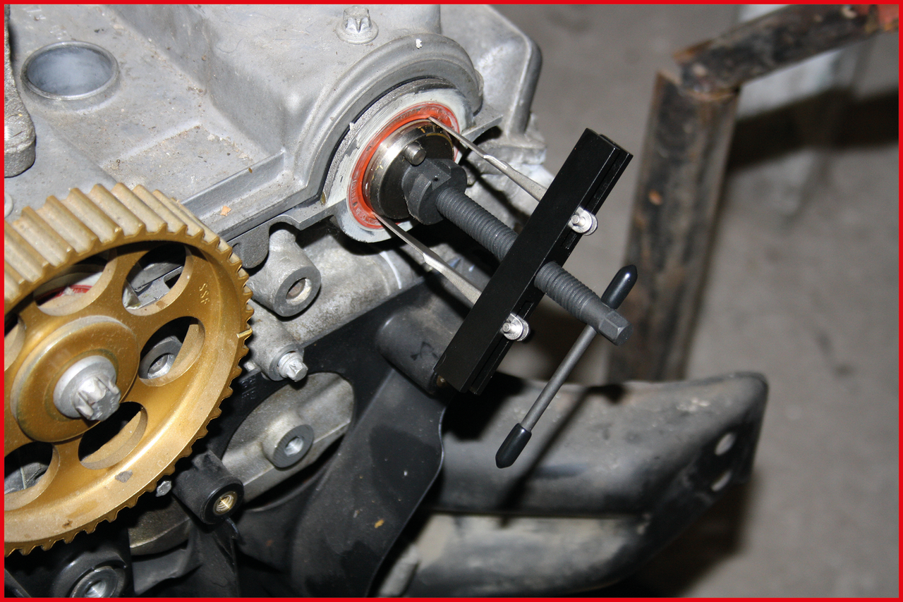 Motor se soukolím a černo-stříbrným nástrojem pro konstruování nebo opravu. V pozadí rozmazané díly automobilu.