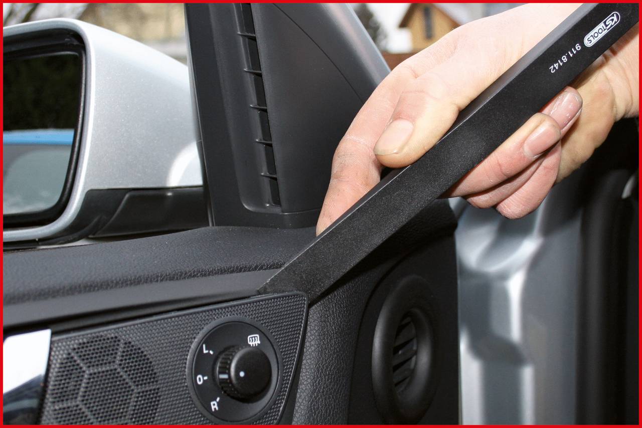 Jedna ruka používá nástroj k odstranění reproduktorové mřížky automobilu.