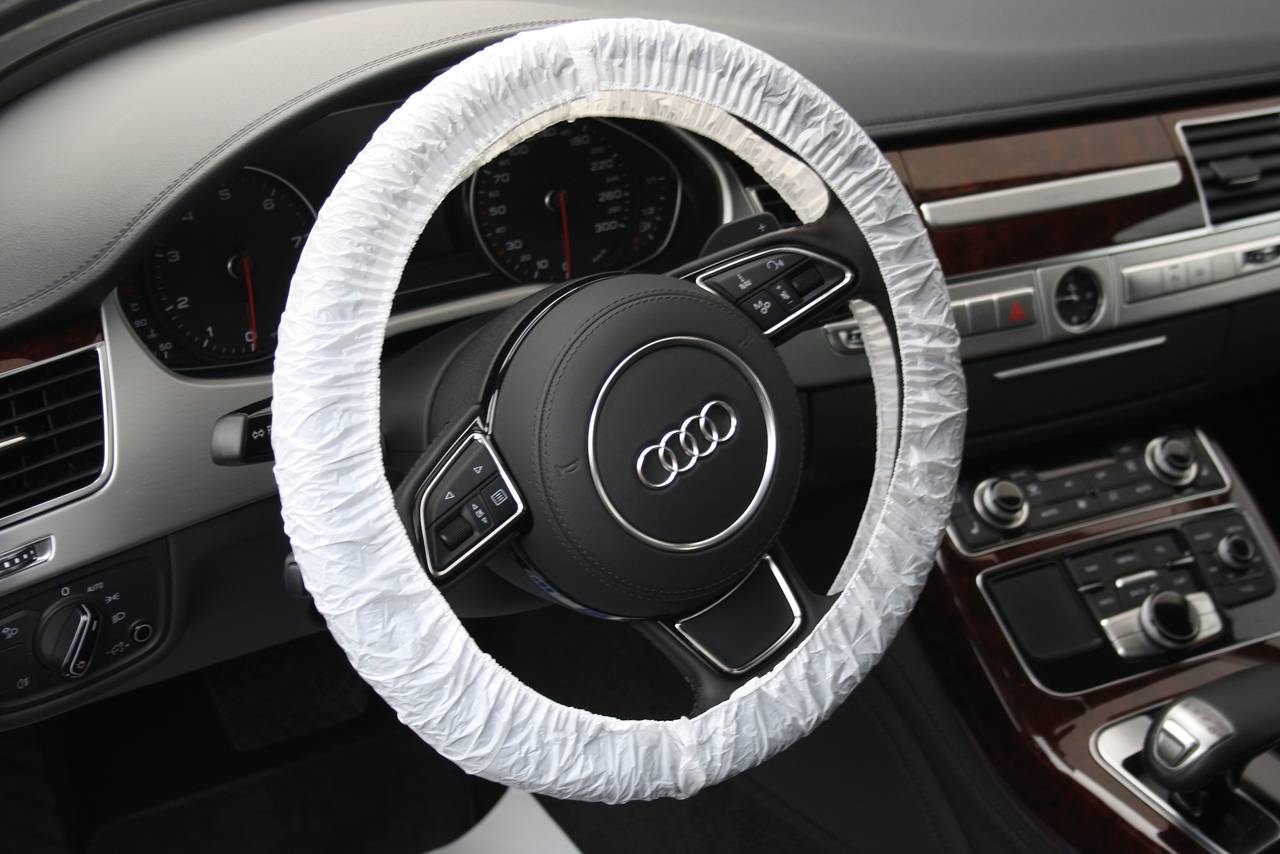 Volant Audi s ochranným potahem. Na volantu jsou viditelná ovládací tlačítka, v pozadí interiér vozu.