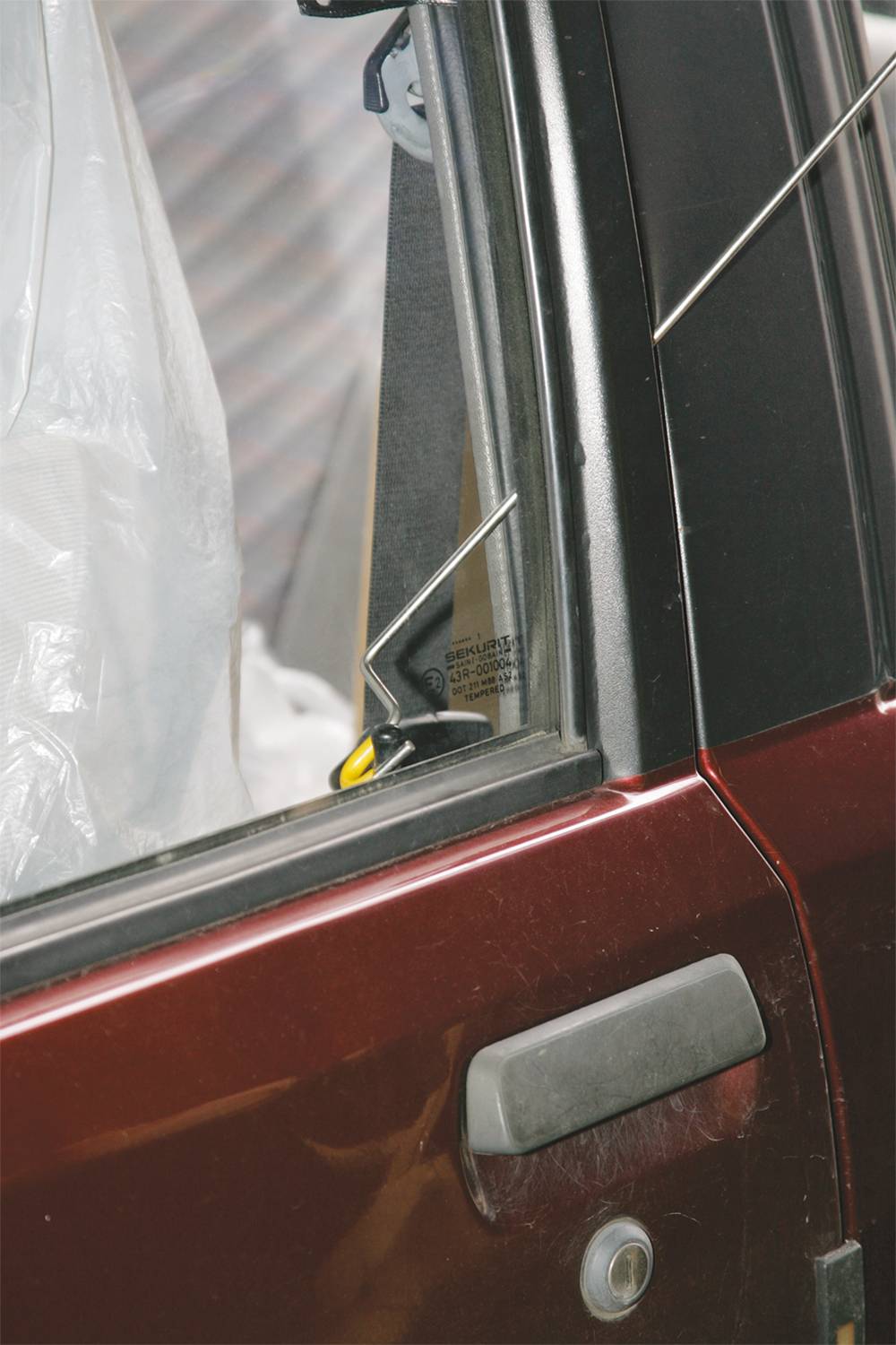 Auto s otevřenými dveřmi a násilně odemčeným zámkem. Je viditelný drát používaný jako nástroj k odemčení vozidla.