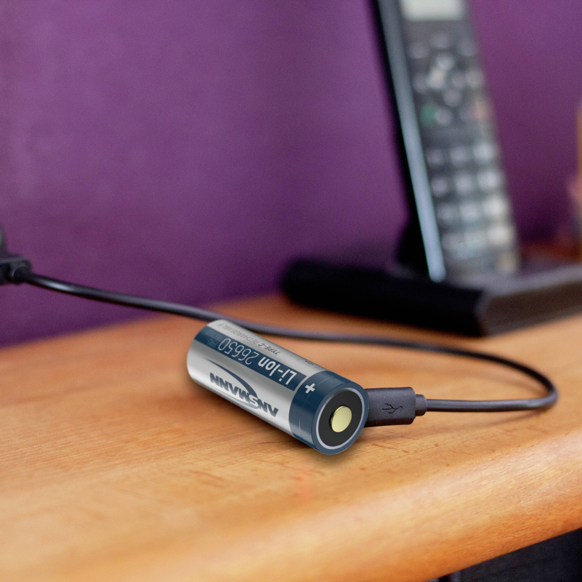 Telefon je nabíjeno na stole pomocí adaptéru na baterie AA, který je připojen přes USB kabel.