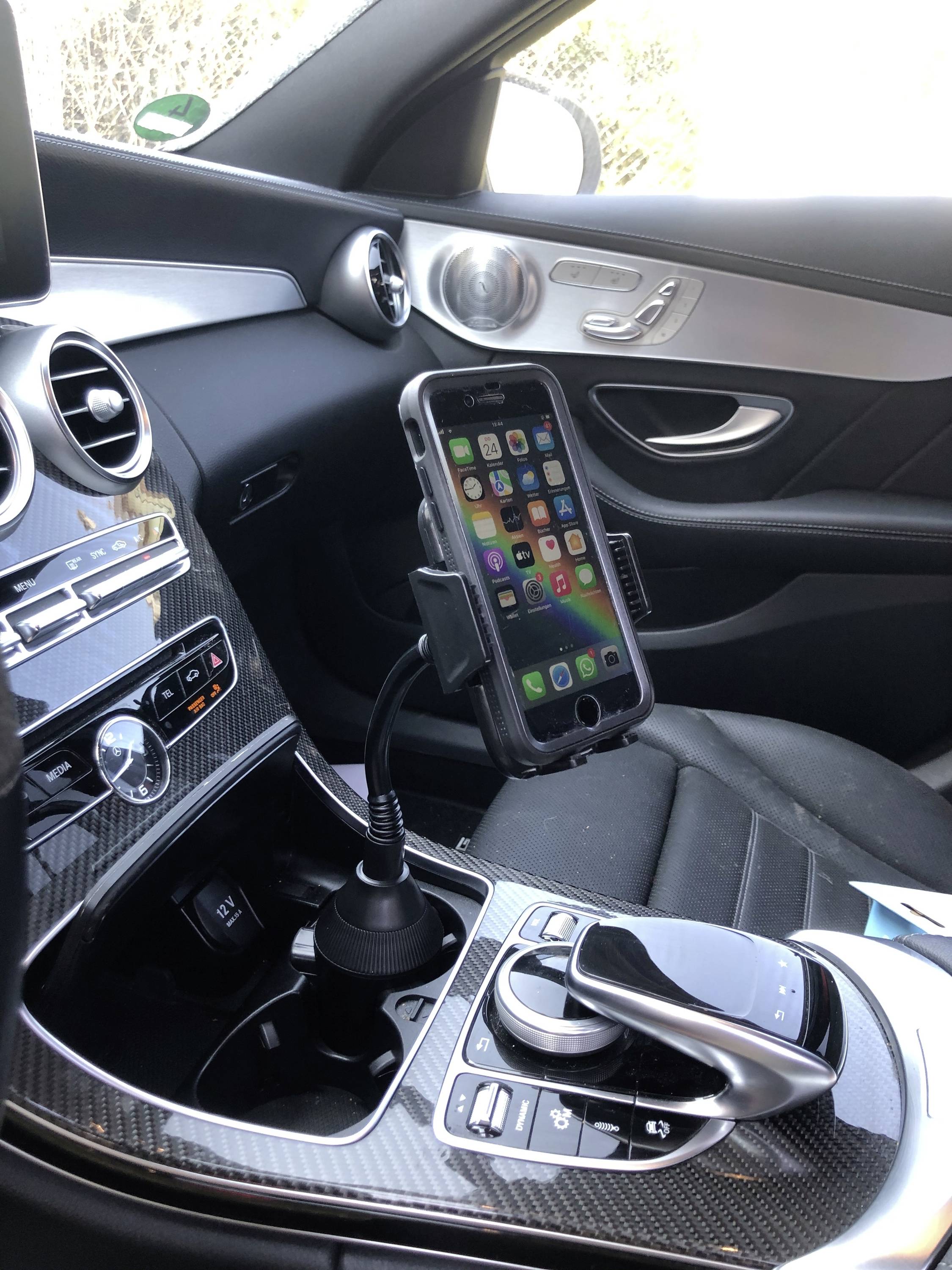 Mobilní telefon je upevněn v držáku v automobilu, na obrazovce jsou viditelné ikony několika aplikací.
