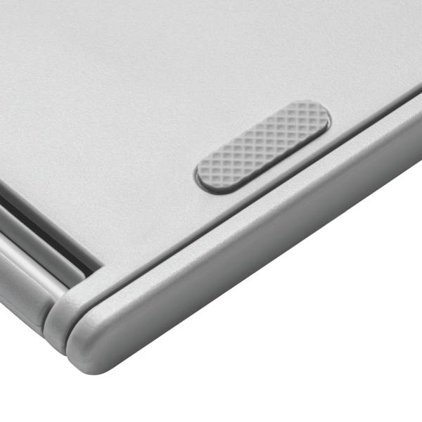 Stříbrný, moderní kovový kloub notebooku v detailním záběru. Je vidět strukturovaná gumová podložka pro stabilizaci na hladkém povrchu.