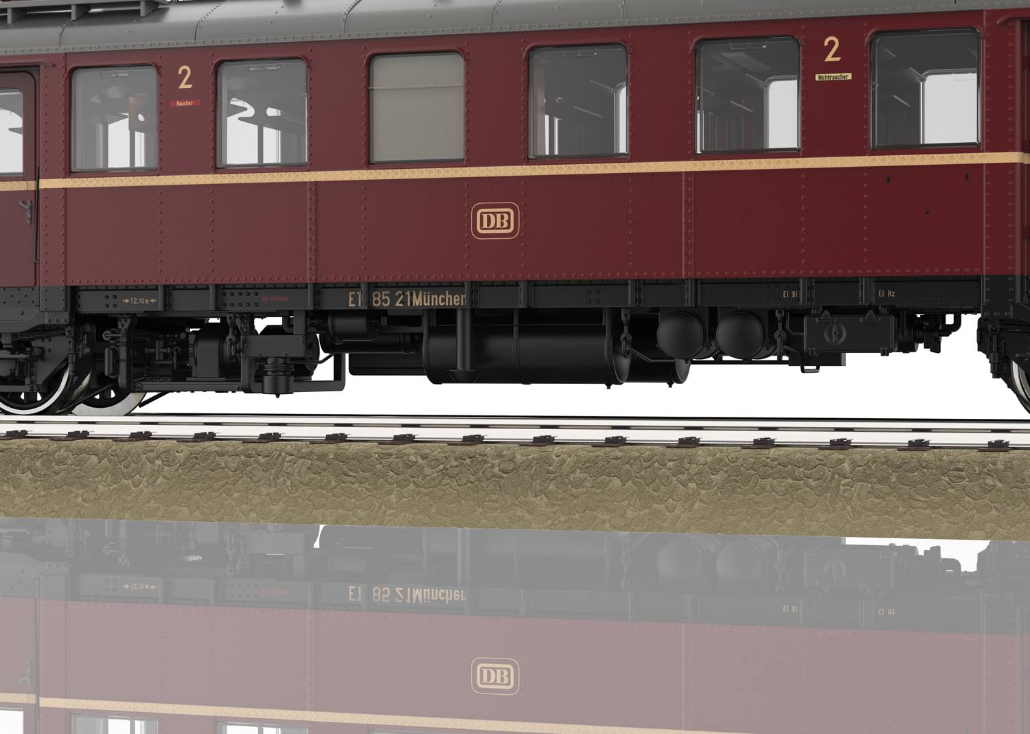 Červený model německého železničního vagonu na kolejích s nápisem 'DB' a 'EL 85 2 Mnichov', v šedo-červeném nátěru.