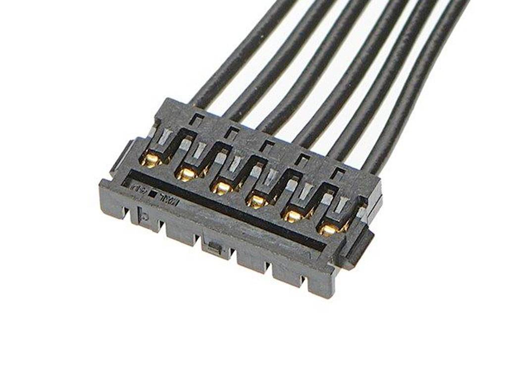 Černá elektrická zástrčka se šesti zlatými kontakty, propojená černými kabely, pohled shora.