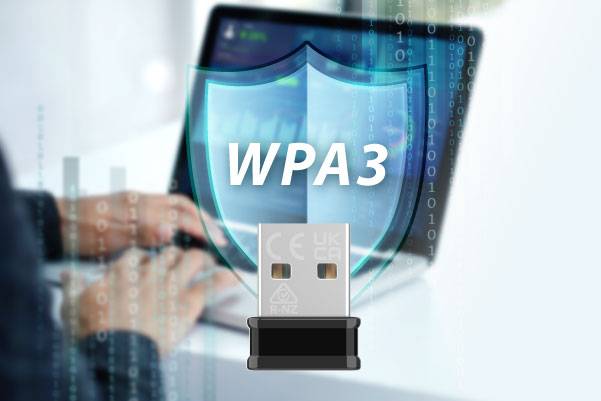 Počítačový monitor zobrazuje bezpečnostní software. V popředí je USB zařízení s nápisem 'WPA3', který se vztahuje k zabezpečení WiFi.