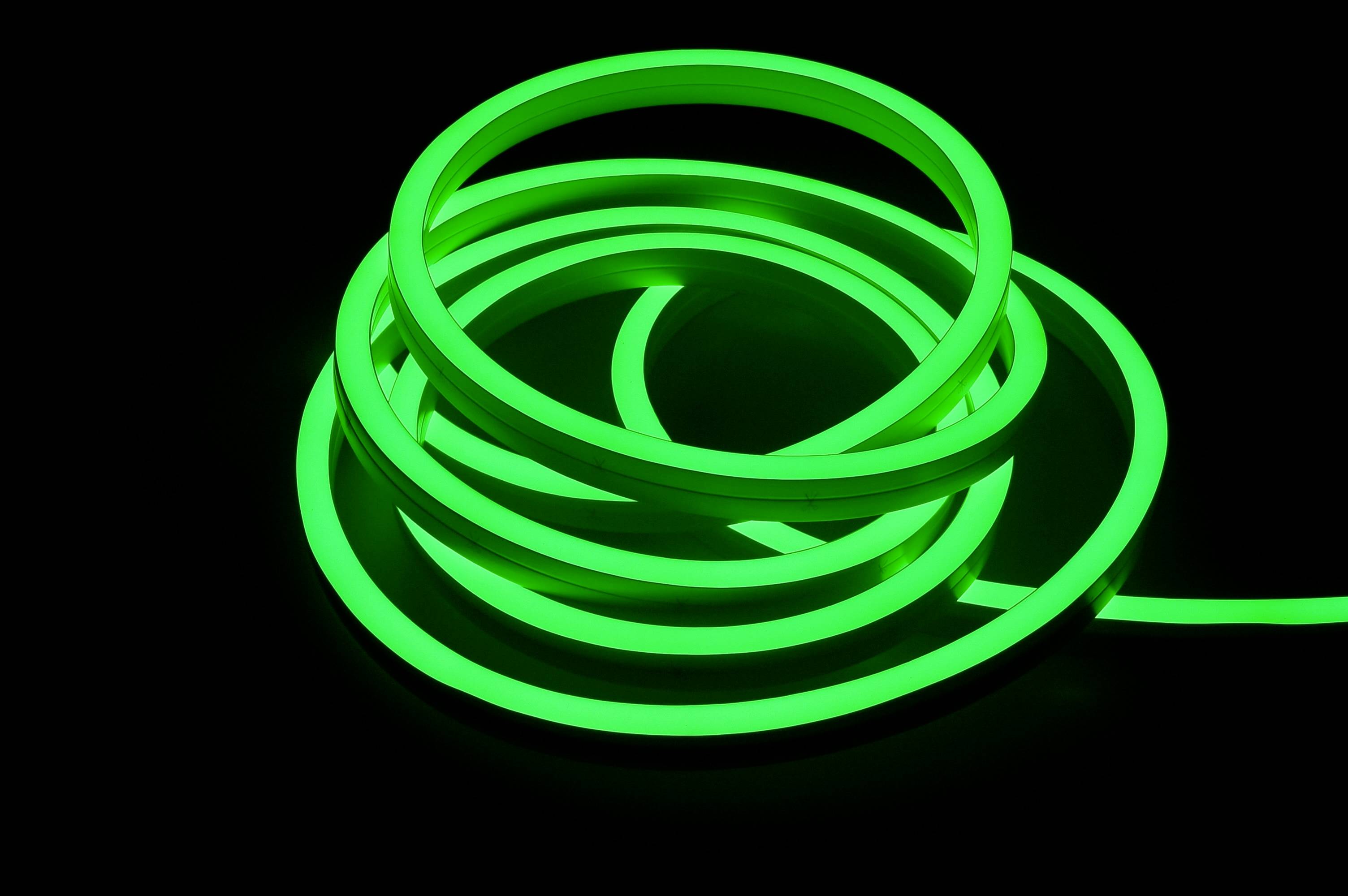 Svítící zelený LED pásek leží v závitech na černém pozadí.