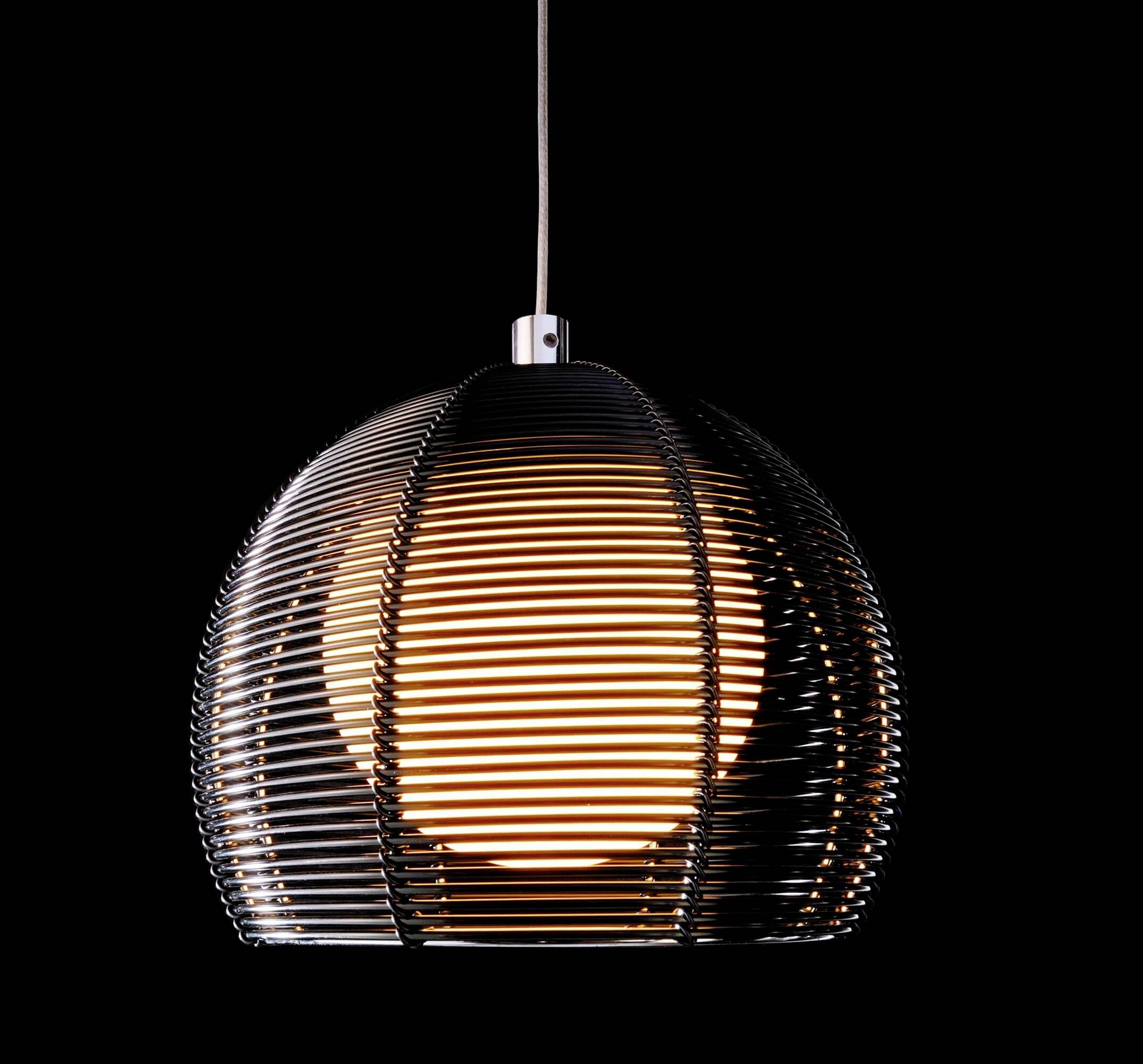 Moderní závěsná lampa s kulatým, proužkovaným stínidlem vyzařujícím teplé světlo. Pozadí je černé.