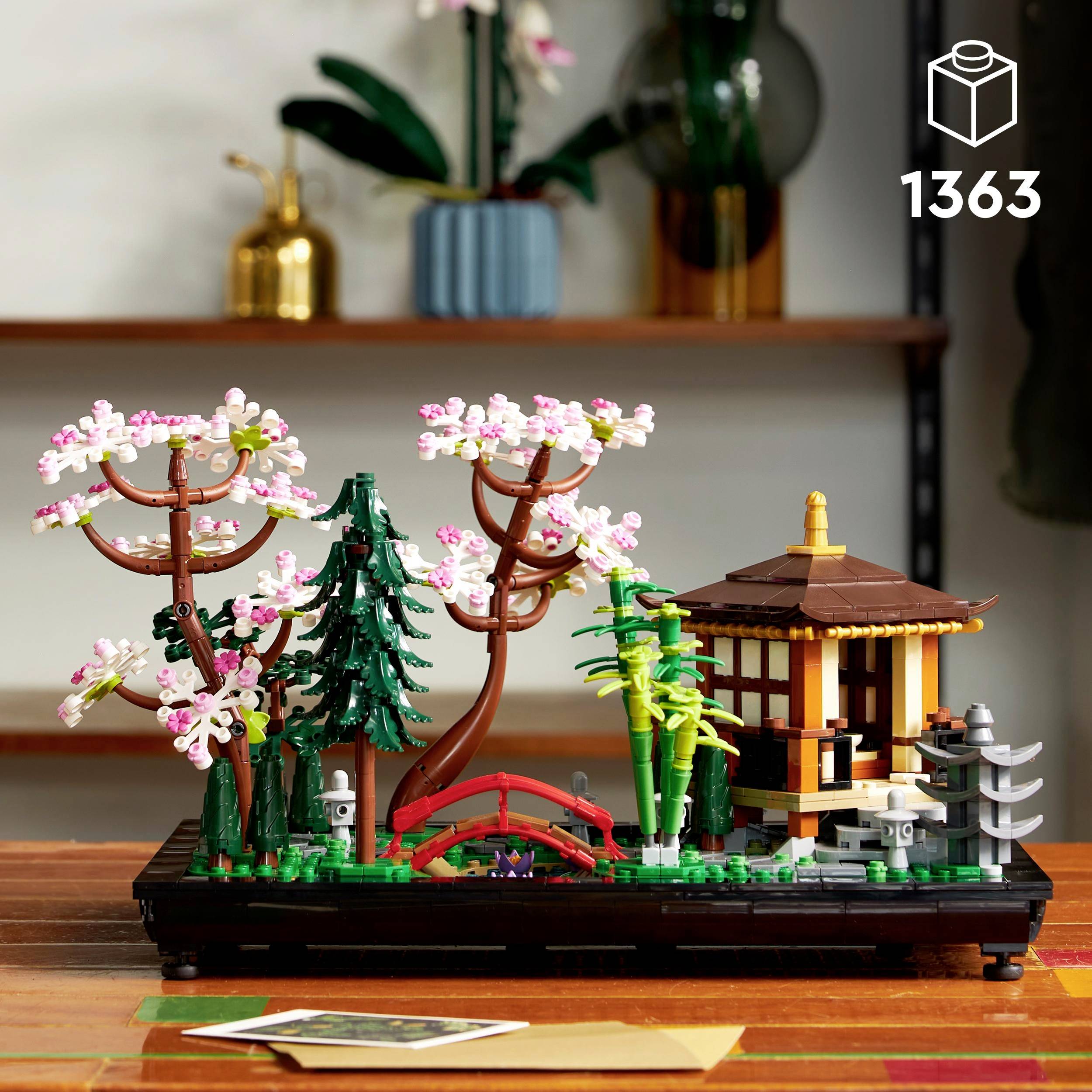 Model LEGO zobrazuje japonskou zahradní krajinu s třešňovými stromy, červeným mostem a pavilonem v tradičním stylu.