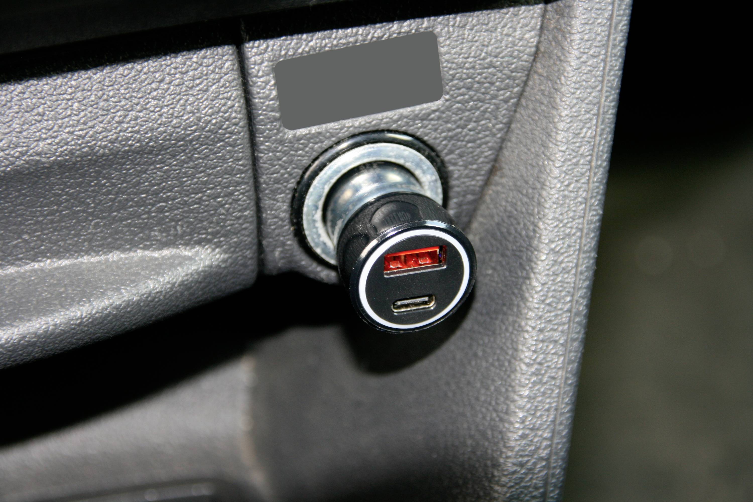 USB nabíjecí adaptér je zastrčen do zásuvky zapalovače v automobilu.