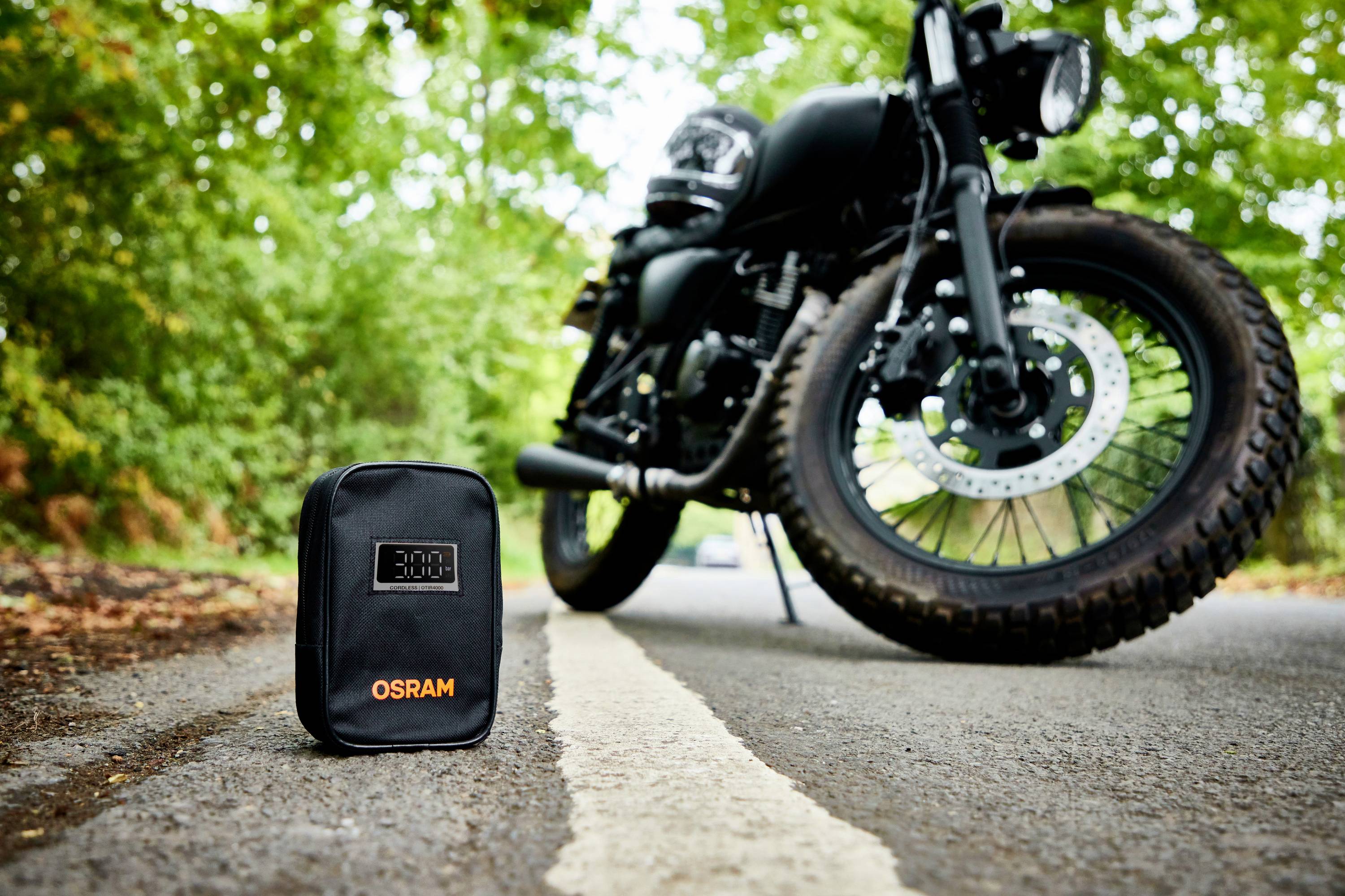 Porucha motocyklu na silnici, v popředí pohotovostní sada OSRAM pro nouzové situace.
