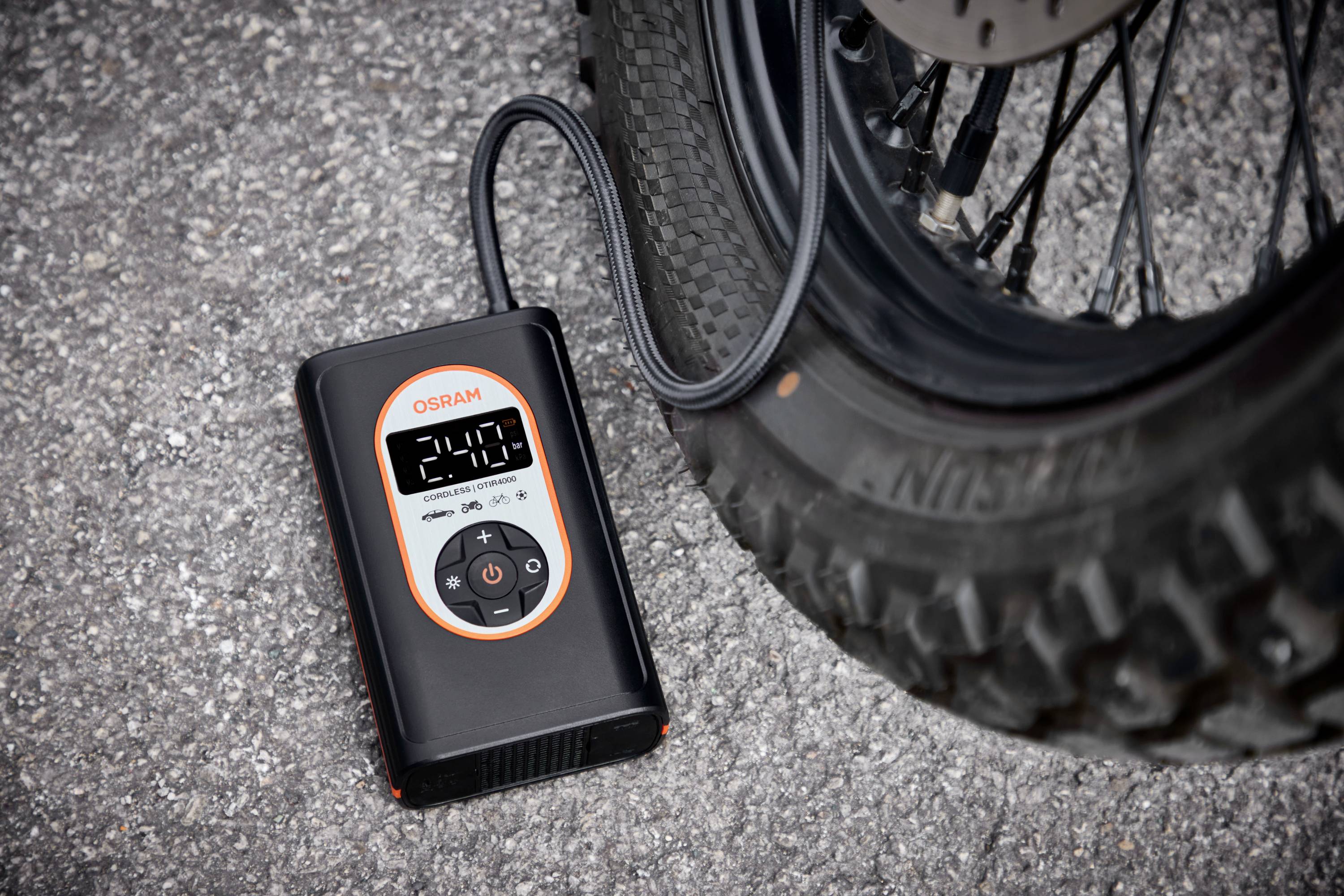 Digitální měřič tlaku vedle motocyklové pneumatiky ukazuje tlak 2,1 baru.
