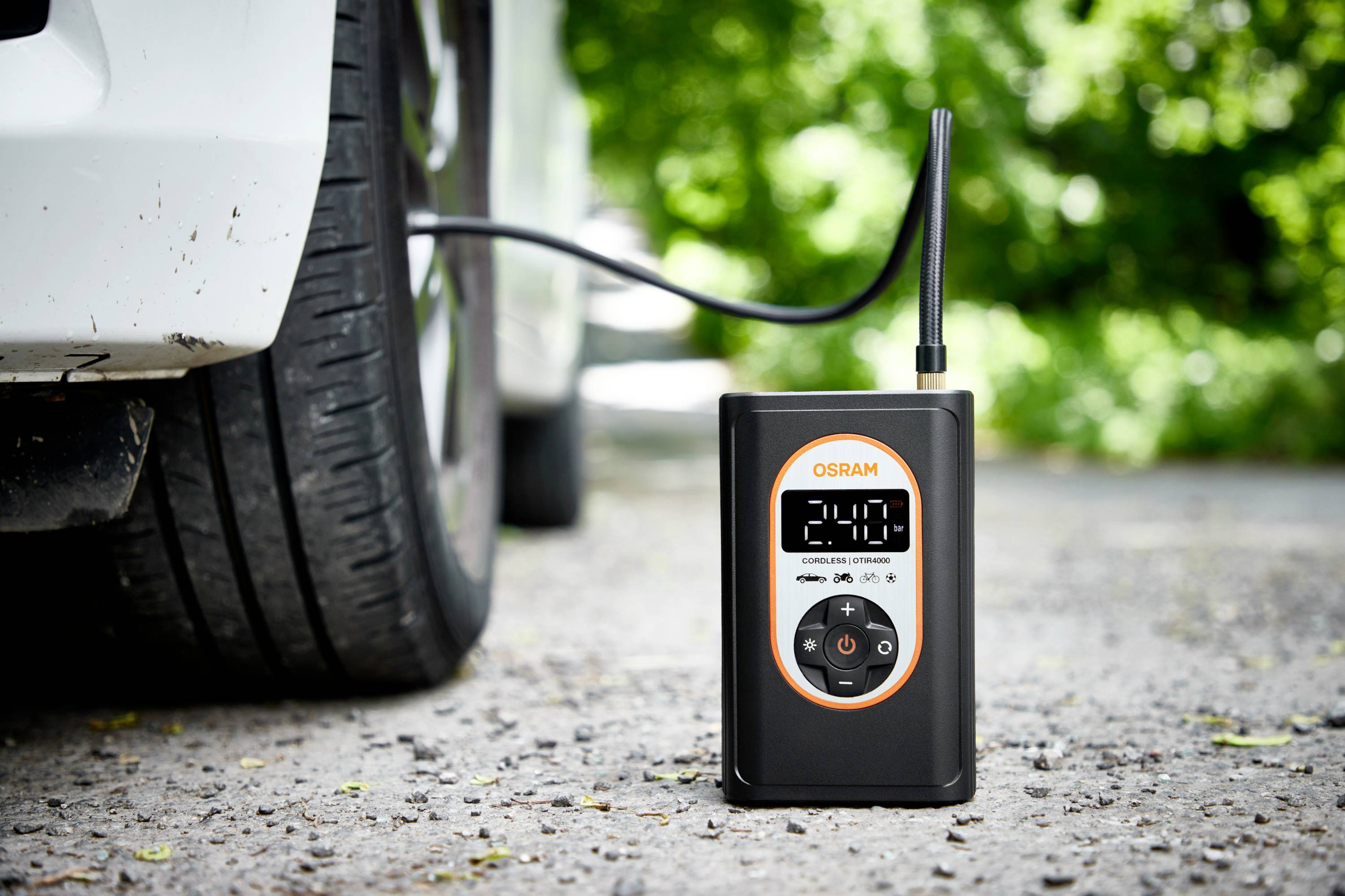 Digitální kompresor ukazuje '2.40' a je připojen k pneumatice automobilu za účelem kontroly nebo nastavení tlaku vzduchu.