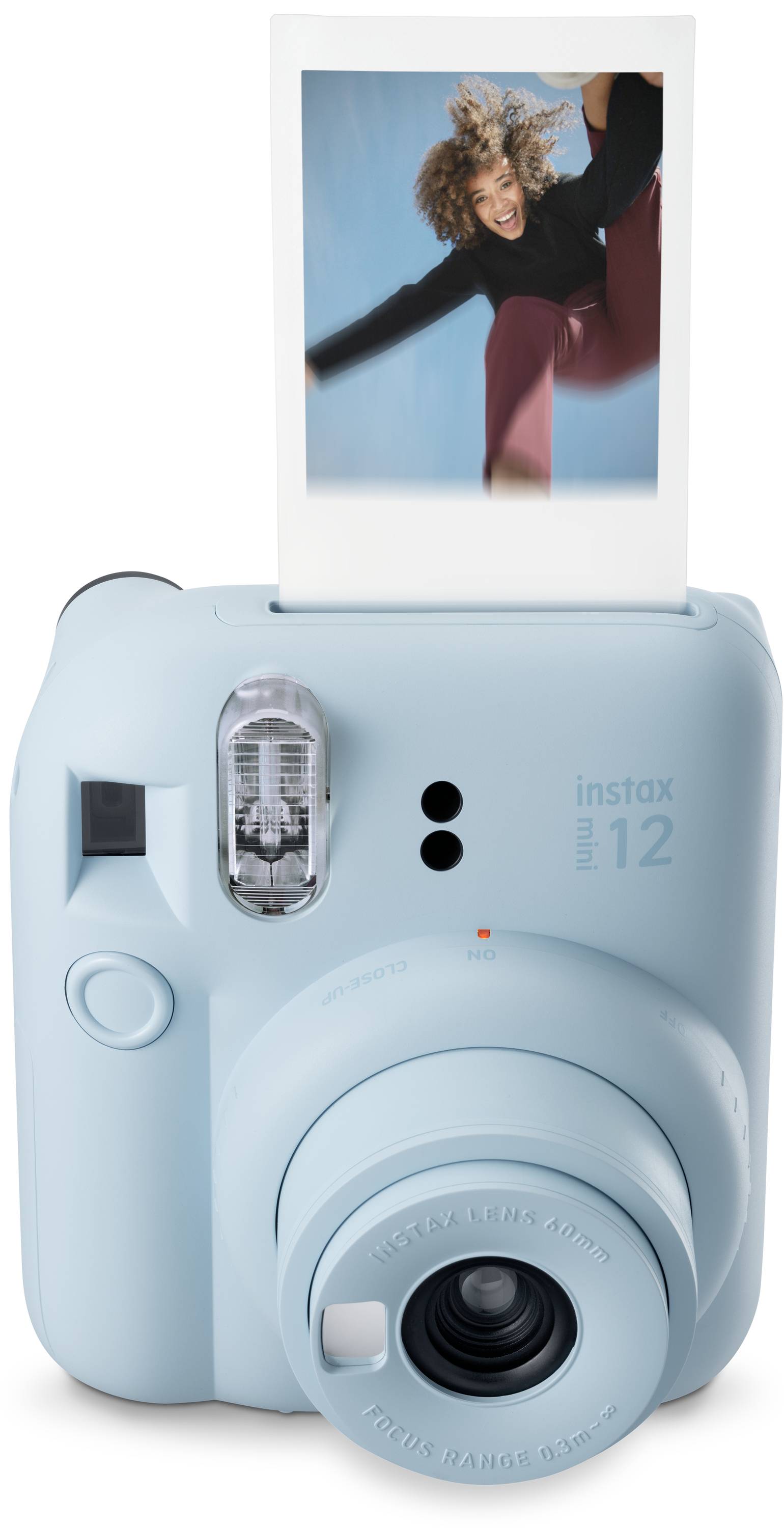Světle modrý instantní fotoaparát s vytištěnou fotografií zobrazující usměvavou osobu.