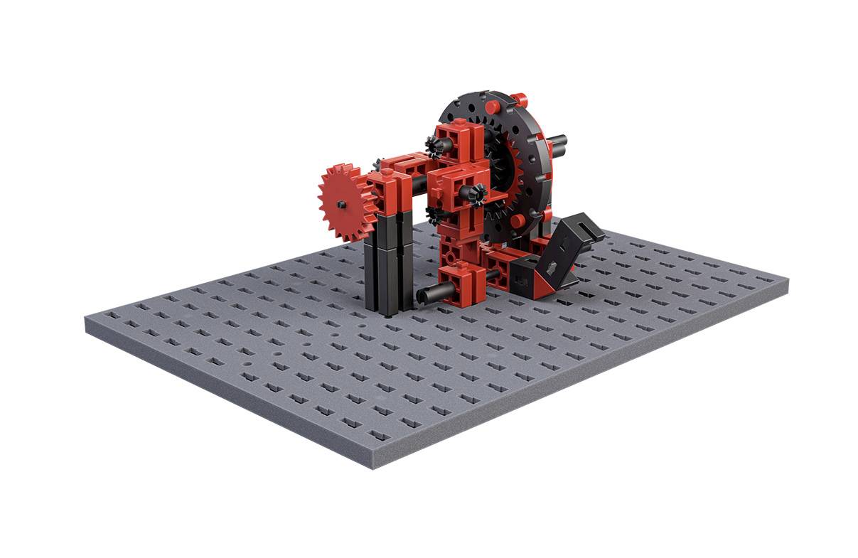Mechanický model z červených a černých stavebních dílků zobrazuje strukturu ozubených kol a páček na šedé základní desce.