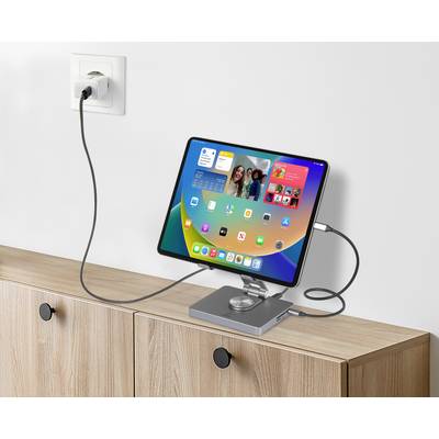 Tablet stojí na stole ve stojánku a je připojeno do elektrické zásuvky, přičemž jeho obrazovka zobrazuje aplikace.