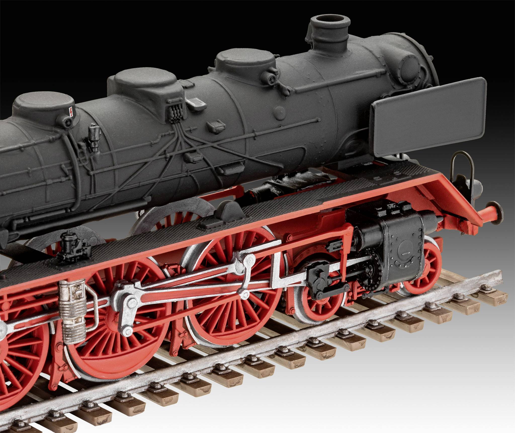 Detailní model historické parní lokomotivy s červenými koly a černým kotlem, umístěný na krátkém úseku kolejí.