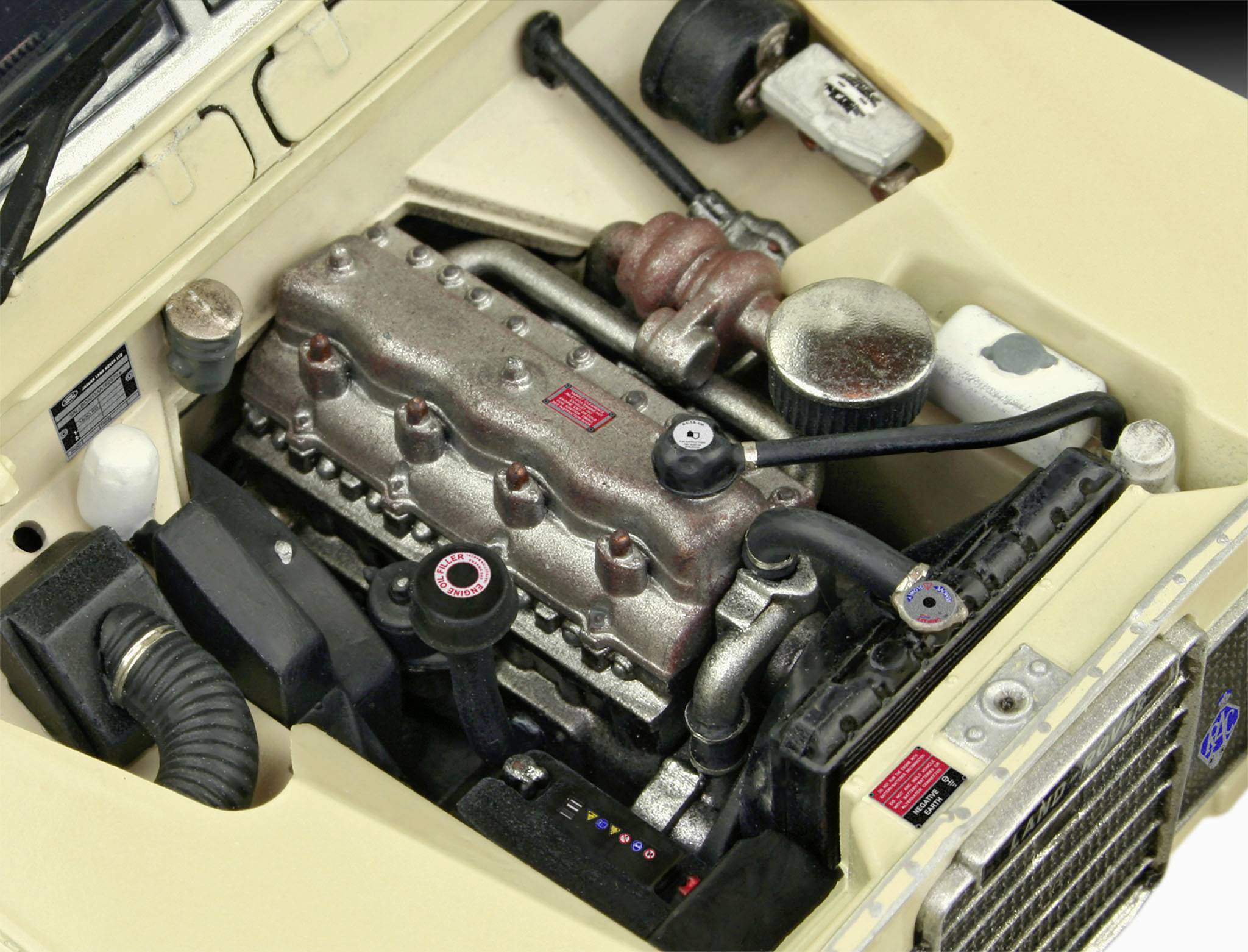 Prostor motoru automobilu s viditelným blokem motoru, hadicemi a dalšími komponenty. Kapota je otevřená.