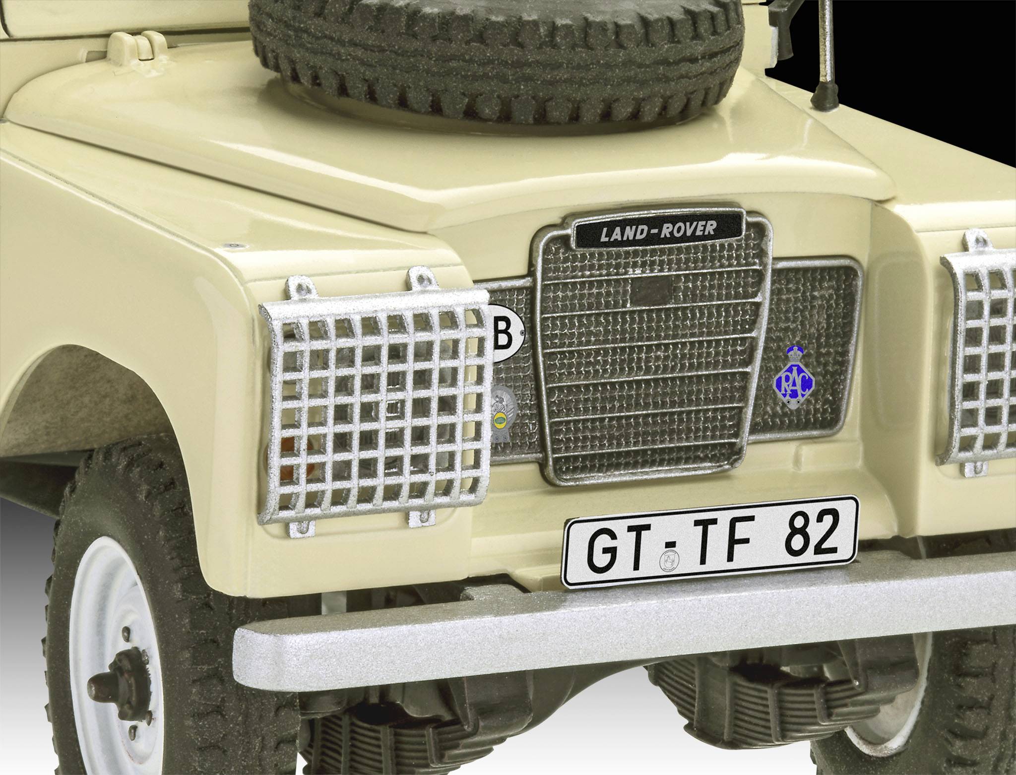 Béžový Land Rover se spare kolem na kapotě. Poznávací značka ukazuje 'GT TF 82'. Auto stojí.