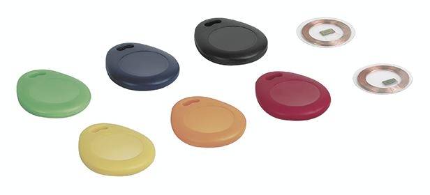 Různé barevné RFID přívěsky na klíče a RFID čipy na bílém pozadí.
