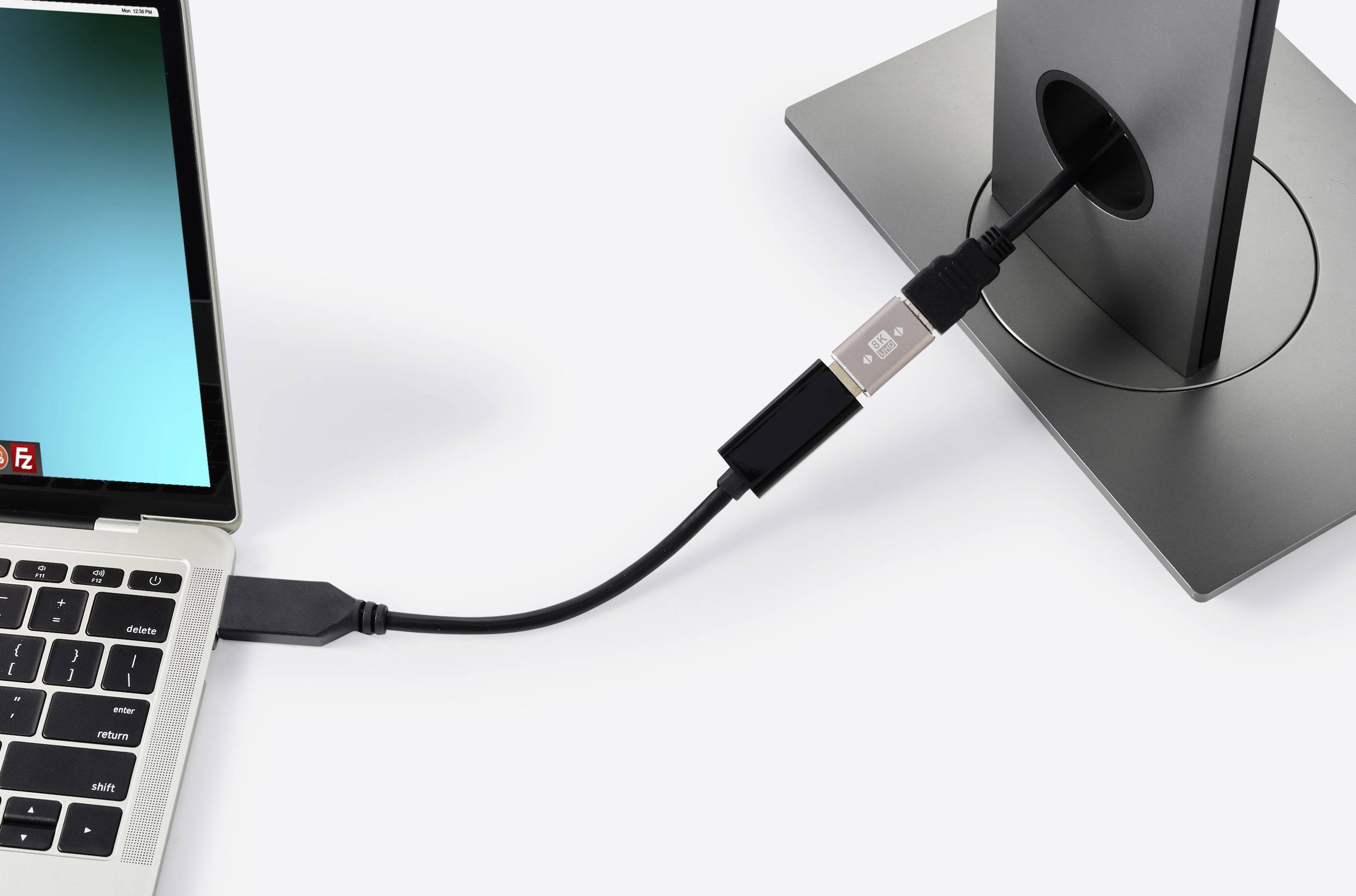 Notebook je připojen k monitoru přes USB kabel, který stojí na kulatém stojanu. Monitor nezobrazuje žádný obsah.