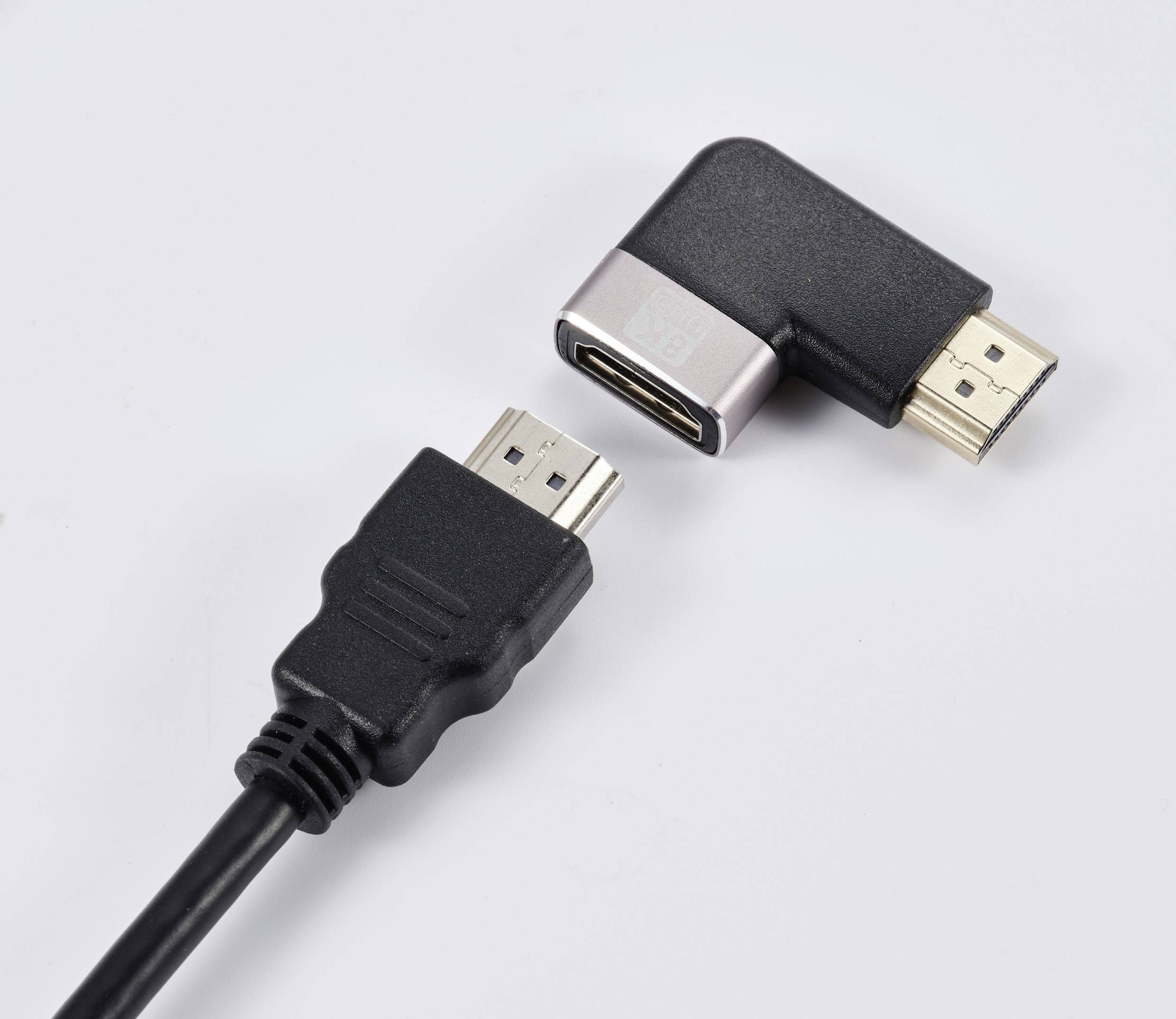 HDMI konektor a HDMI úhlový adaptér na bílém pozadí. Adaptér umožňuje pravoúhlé připojení, aby se ušetřilo místo nebo zpřístupnily špatně dostupné přípojky.