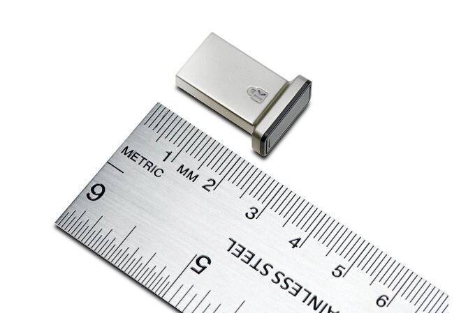 Vedle pravítka leží USB flash disk, které ukazuje jeho délku. Disk měří přibližně 2 cm a má kovový kryt.
