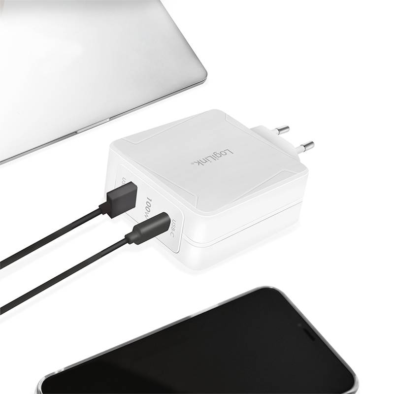 Dva černé USB kabely jsou připojeny k bílé multifunkční nabíječce, která leží vedle notebooku a smartphonu.