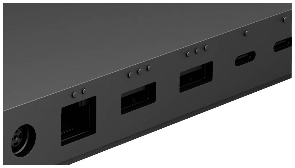 Černý spodní panel zařízení s několika konektory, včetně USB portů a ethernetového připojení, na bílém pozadí.