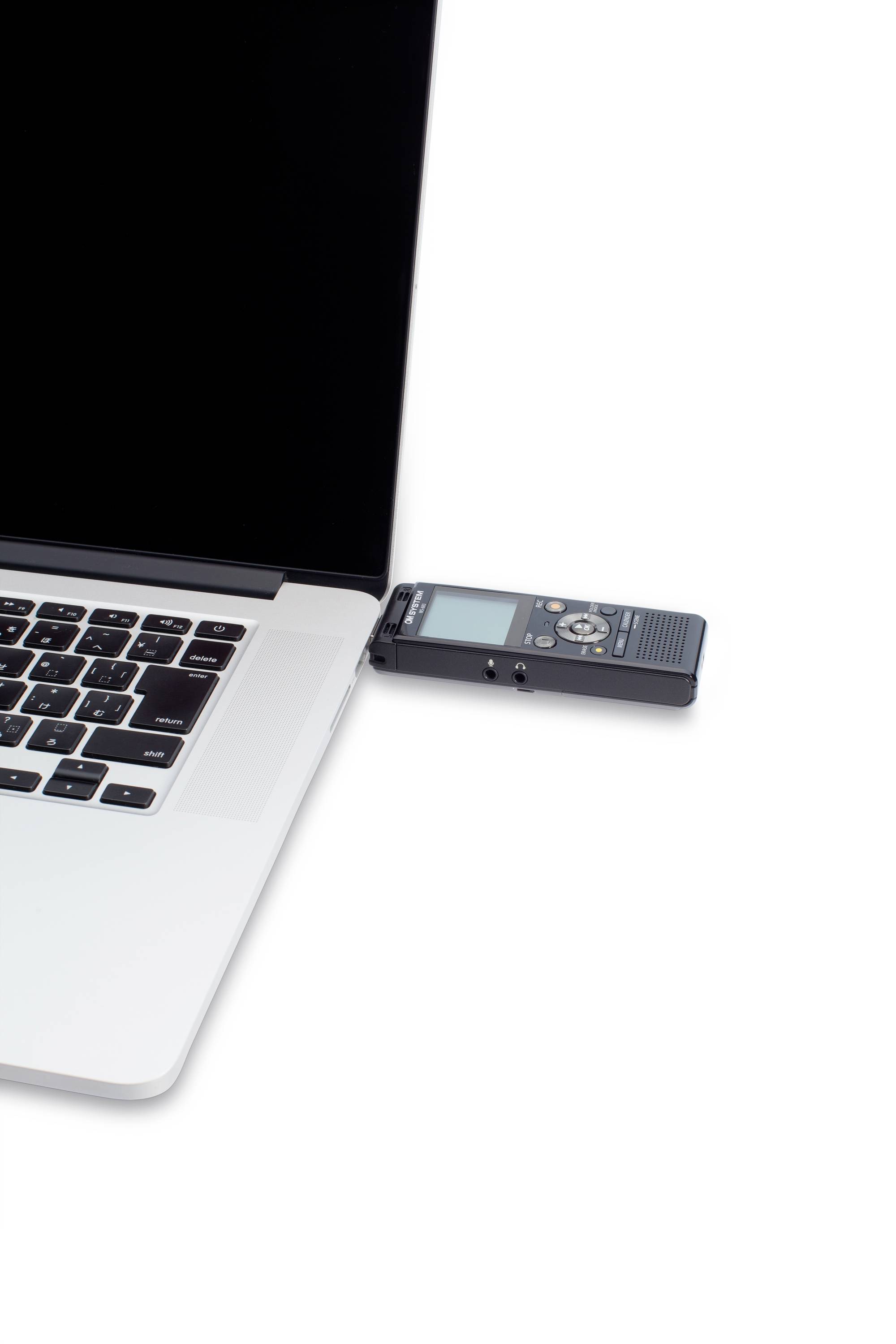 Notebook s připojeným digitálním audio rekordérem. Rekordér je připojen přes USB a umístěn vedle touchpadu.