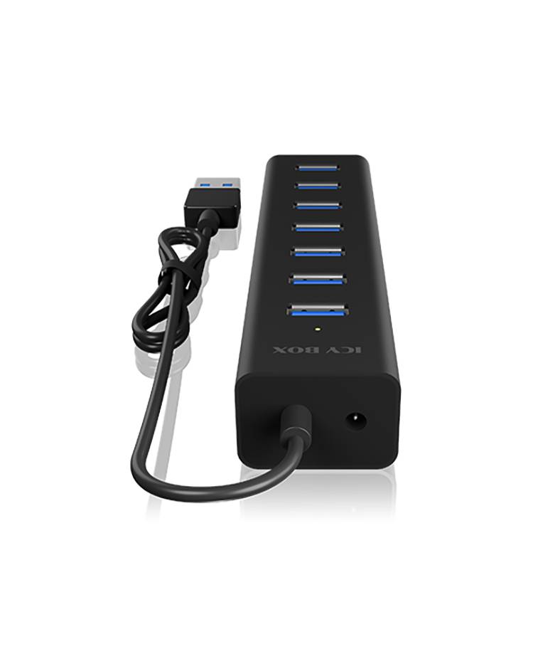 Černý USB hub se sedmi USB porty a připojeným USB kabelem, který leží na bílém povrchu.