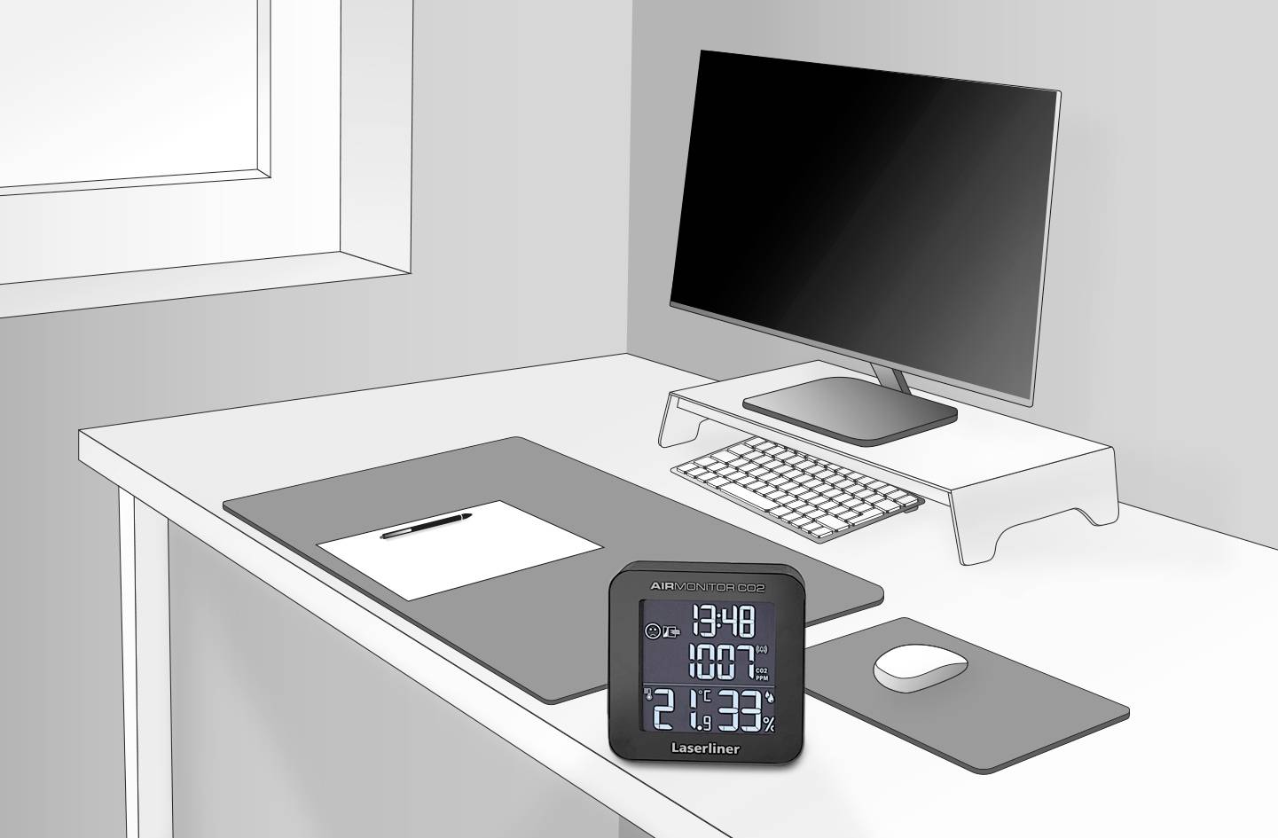 Psací stůl s monitorem, klávesnicí, myší a poznámkovým blokem. V popředí digitální termo-hygrometr s ukazatelem teploty a vlhkosti vzduchu.