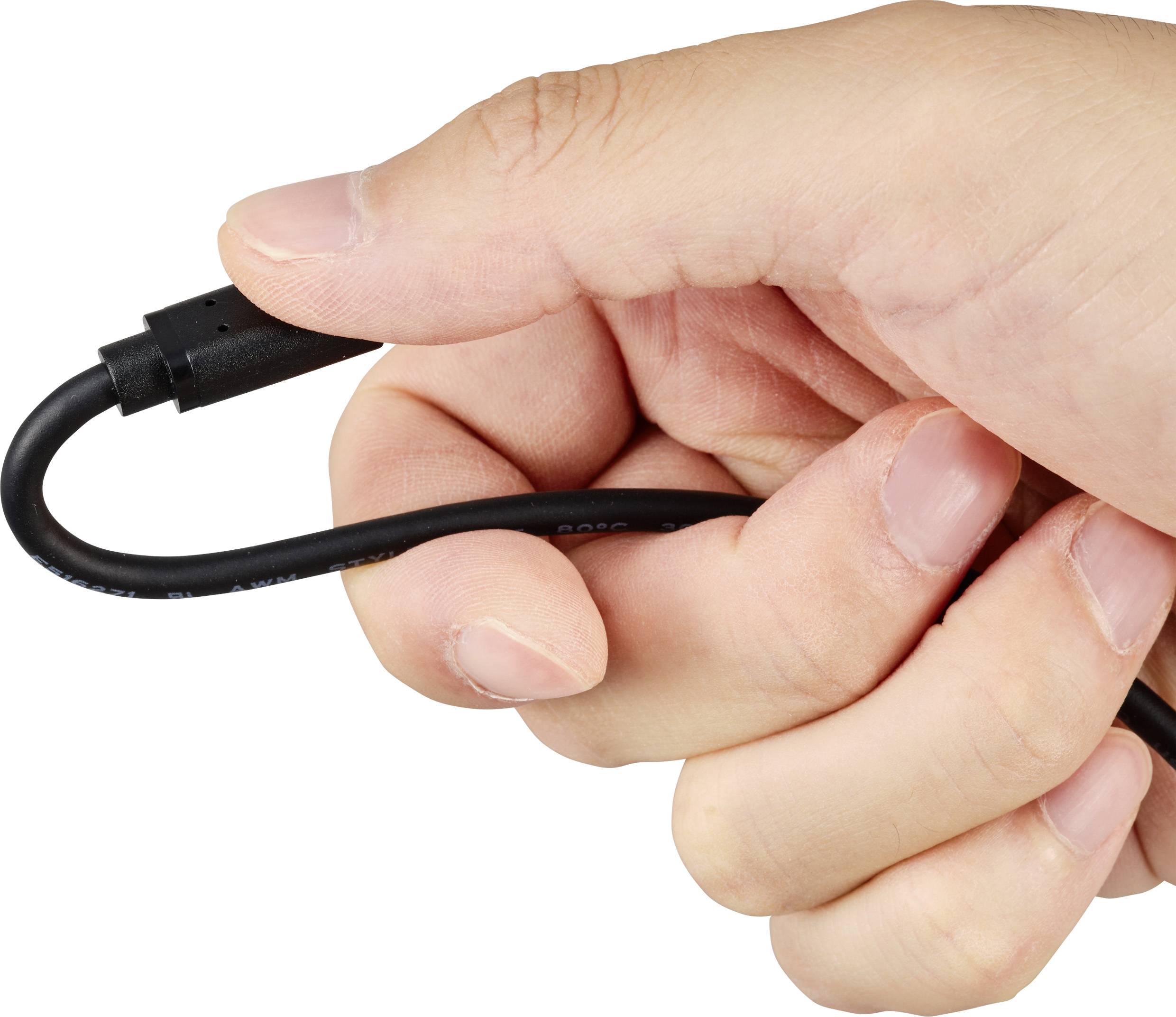 Jedna ruka drží černý kabel s kulatou zástrčkou.