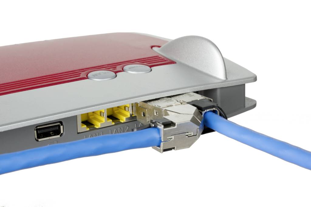 Červený WLAN router se dvěma modrými síťovými kabely zapojenými do konektorů na zadní straně.