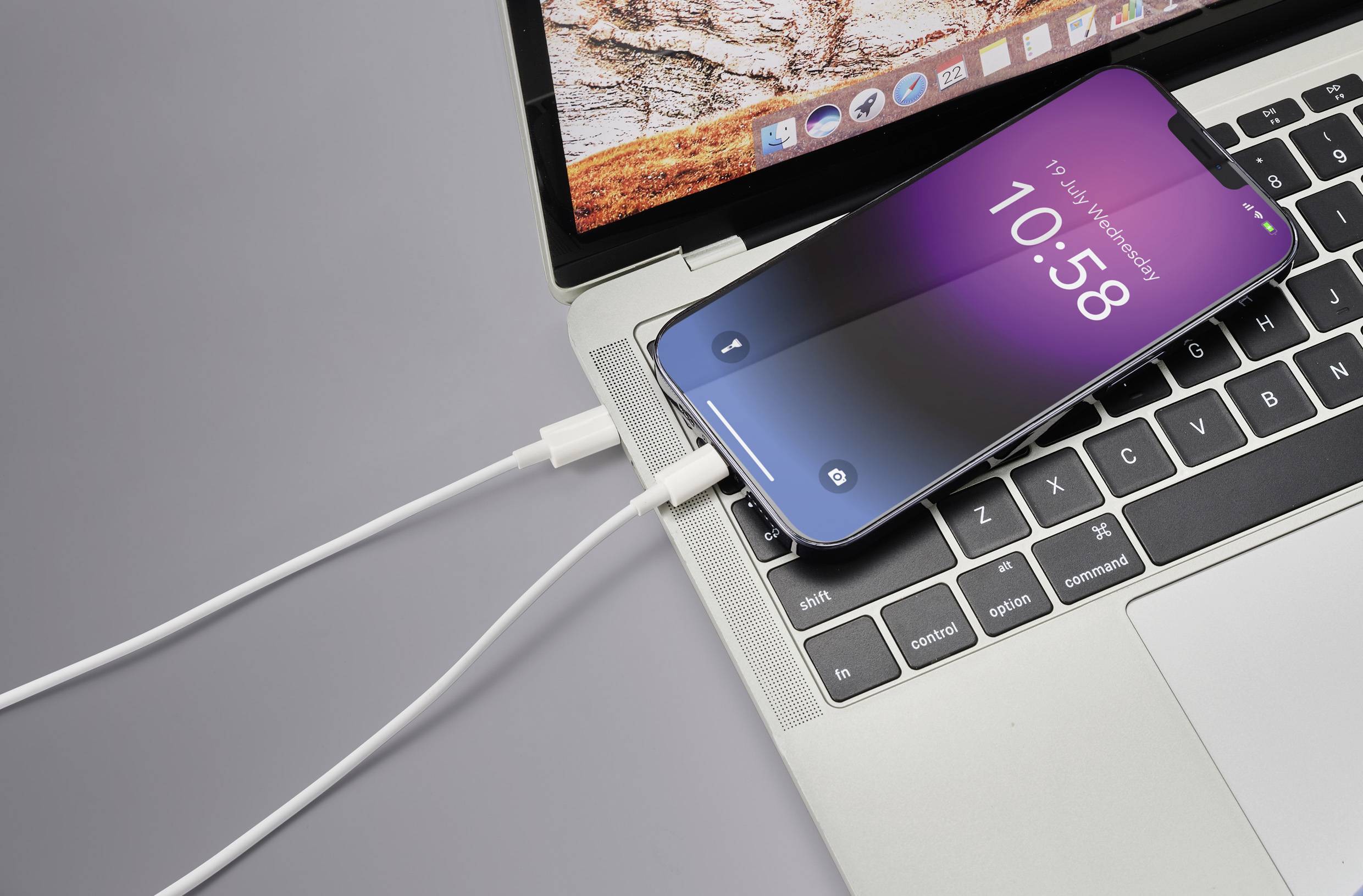 Smartphone s fialovým displejem je připojeno kabelem k laptopU. Displej zobrazuje '10:58'.