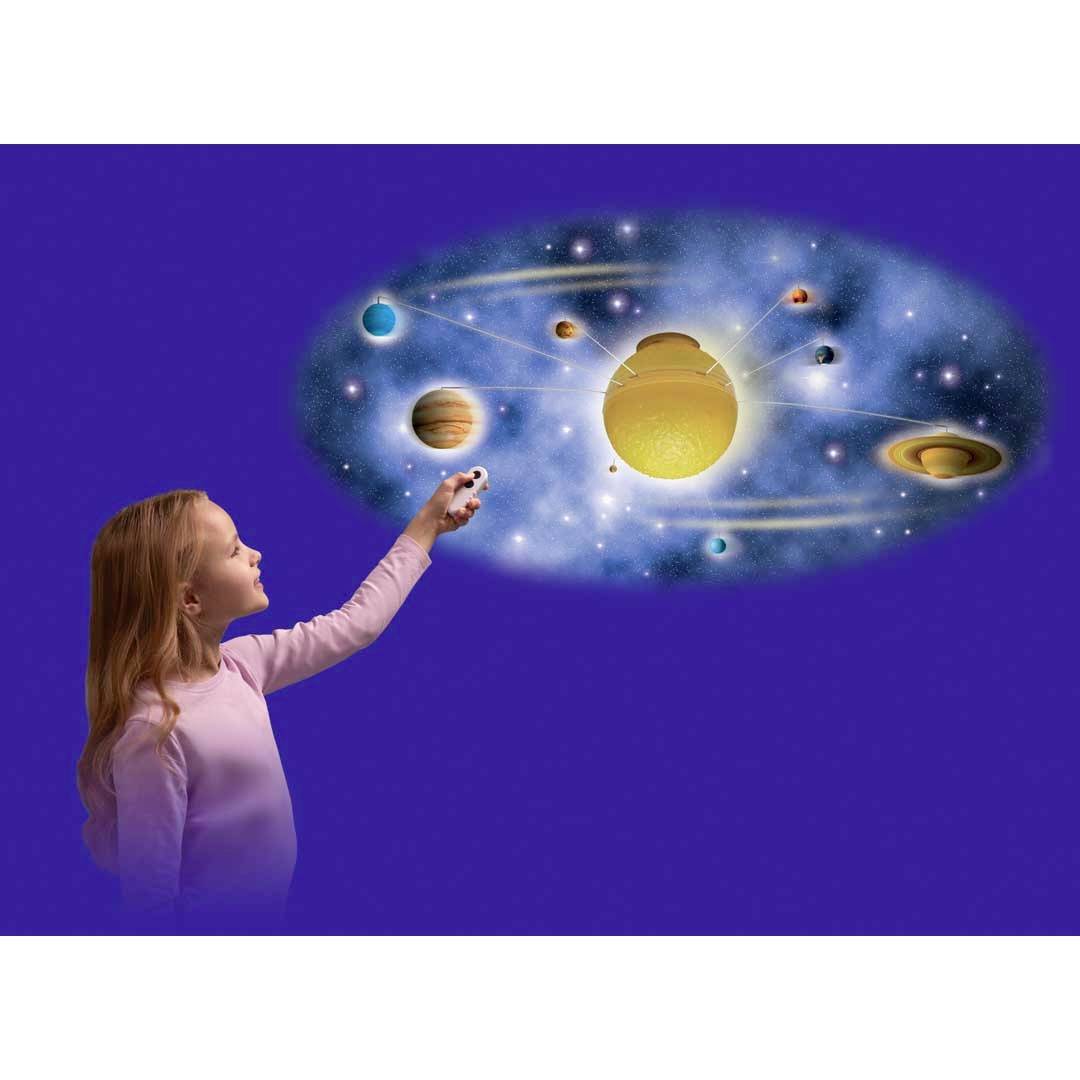 Dívka ukazuje na model sluneční soustavy s různými planetami obíhajícími kolem centrální hvězdy na modrém pozadí.