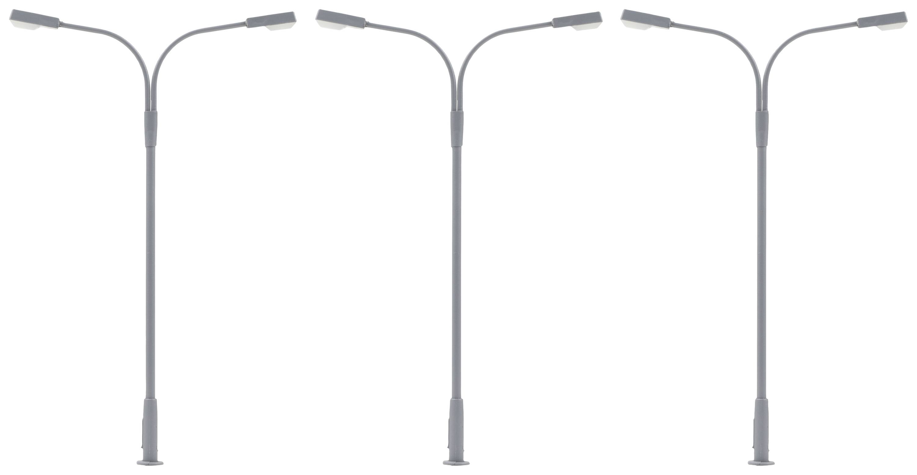Tři moderní pouliční lampy s dvojitými světly na bílém pozadí.