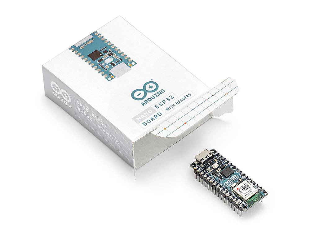 Arduino Nano ESP32 deska, částečně vybalená, leží vedle své krabičky. Deska je vybavena USB konektorem.