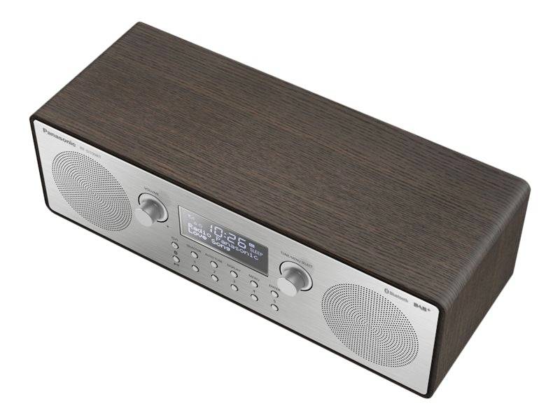 Dřevěné rádio s digitálním displejem zobrazuje '10:26', obklopené reproduktory a ovládacími tlačítky na kovovém povrchu.