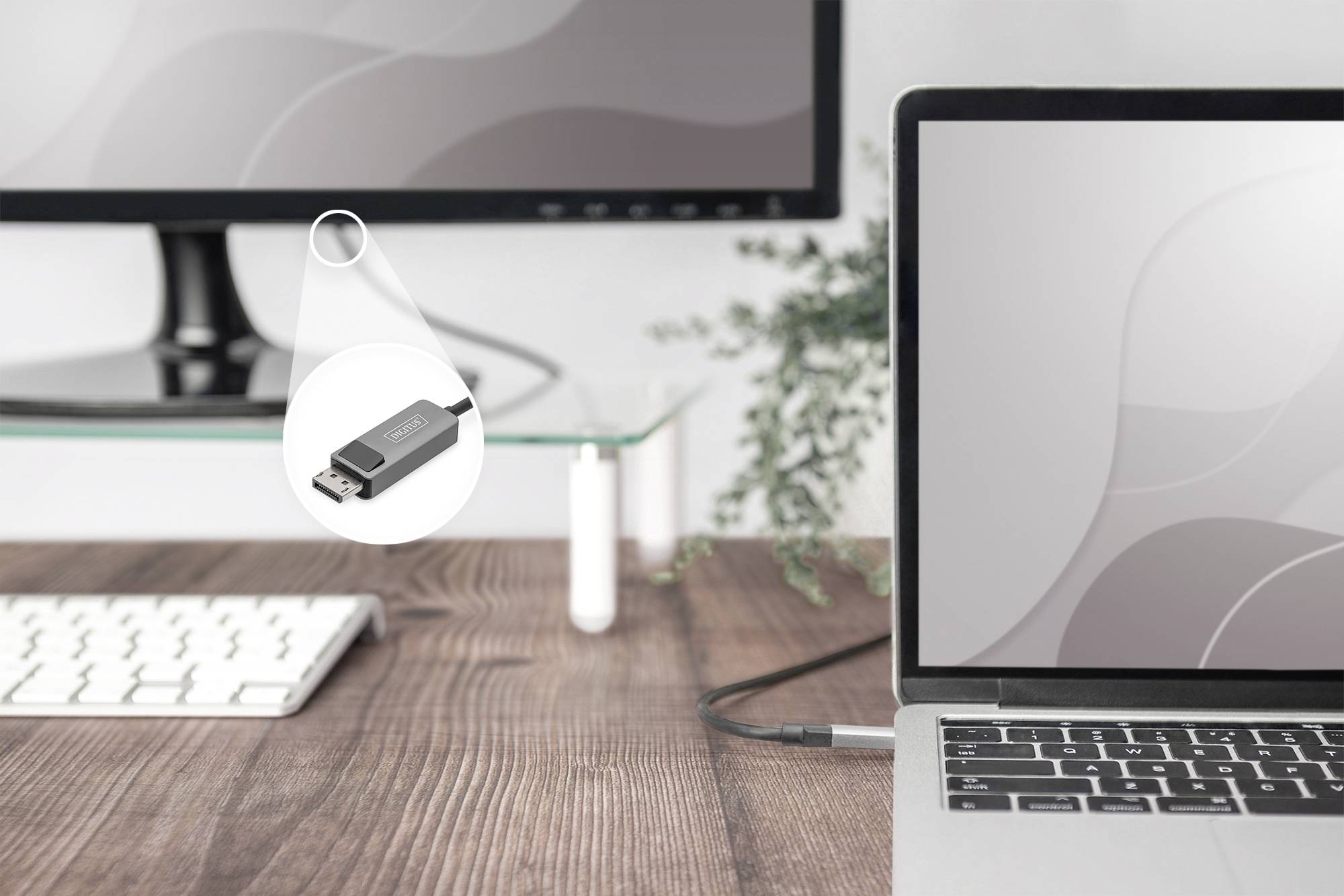 Laptop a monitor jsou propojeny adaptérem USB-C. Adaptér leží na dřevěném stole vedle klávesnice.