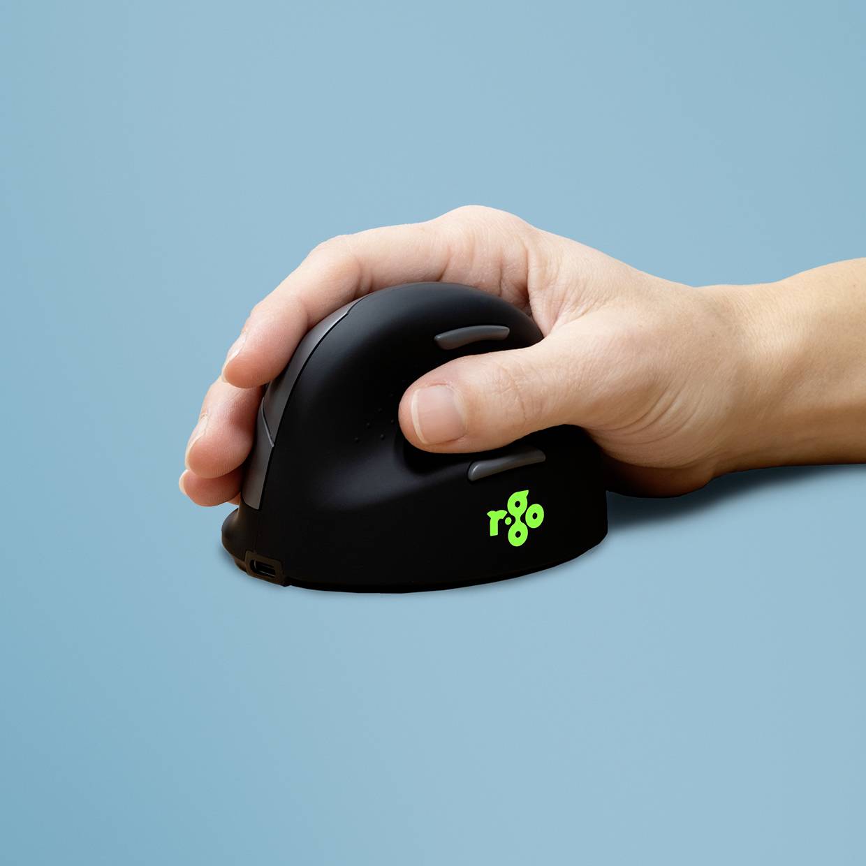 Jedna ruka drží ergonomickou vertikální myš na modrém pozadí. Logo na myši je zelené a zobrazuje nápis "rgo".