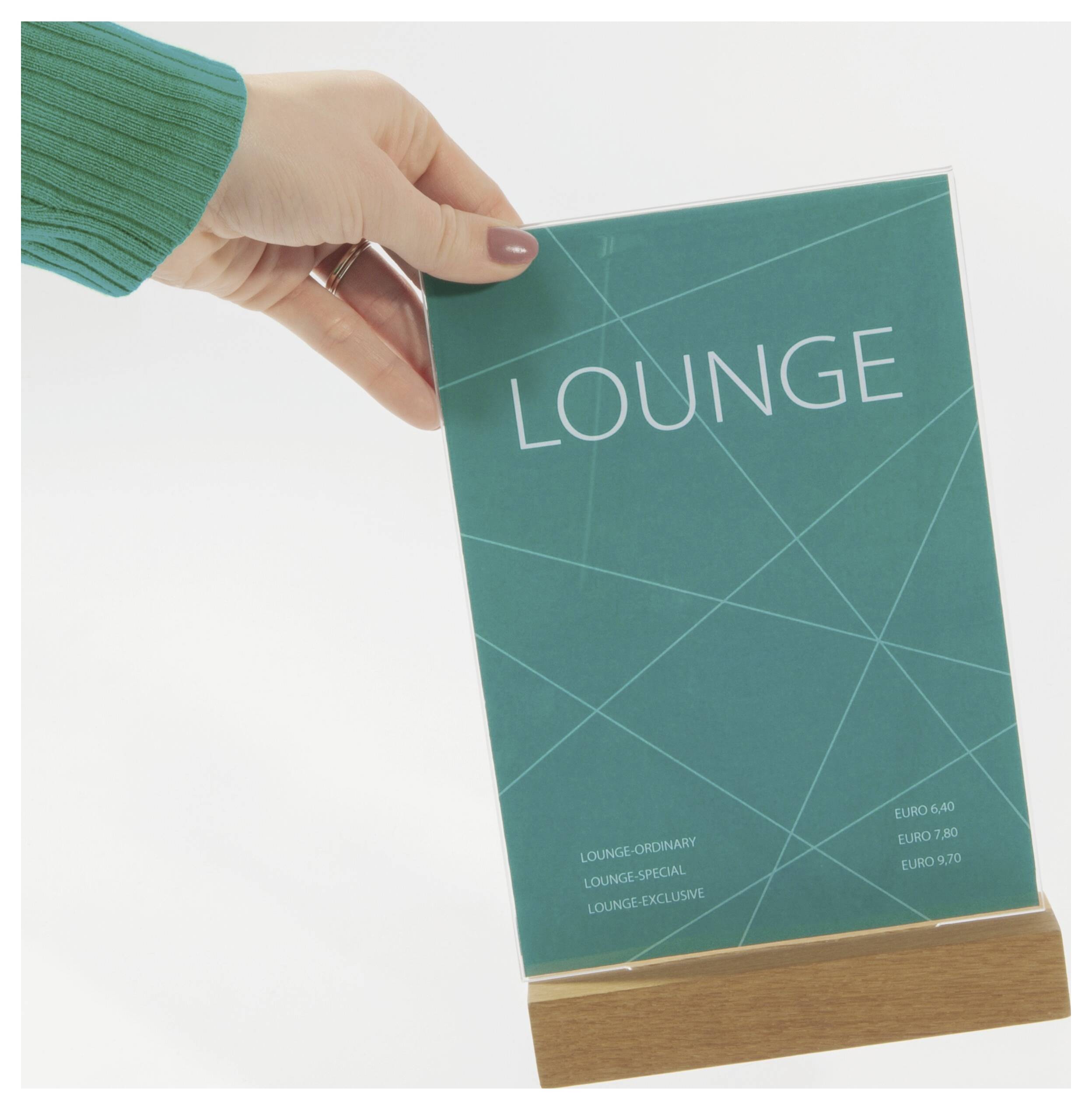 Ruka držící tyrkysový leták nebo menu "LOUNGE" s dřevěnou podstavou, zobrazeno na jednobarevném bílém pozadí.