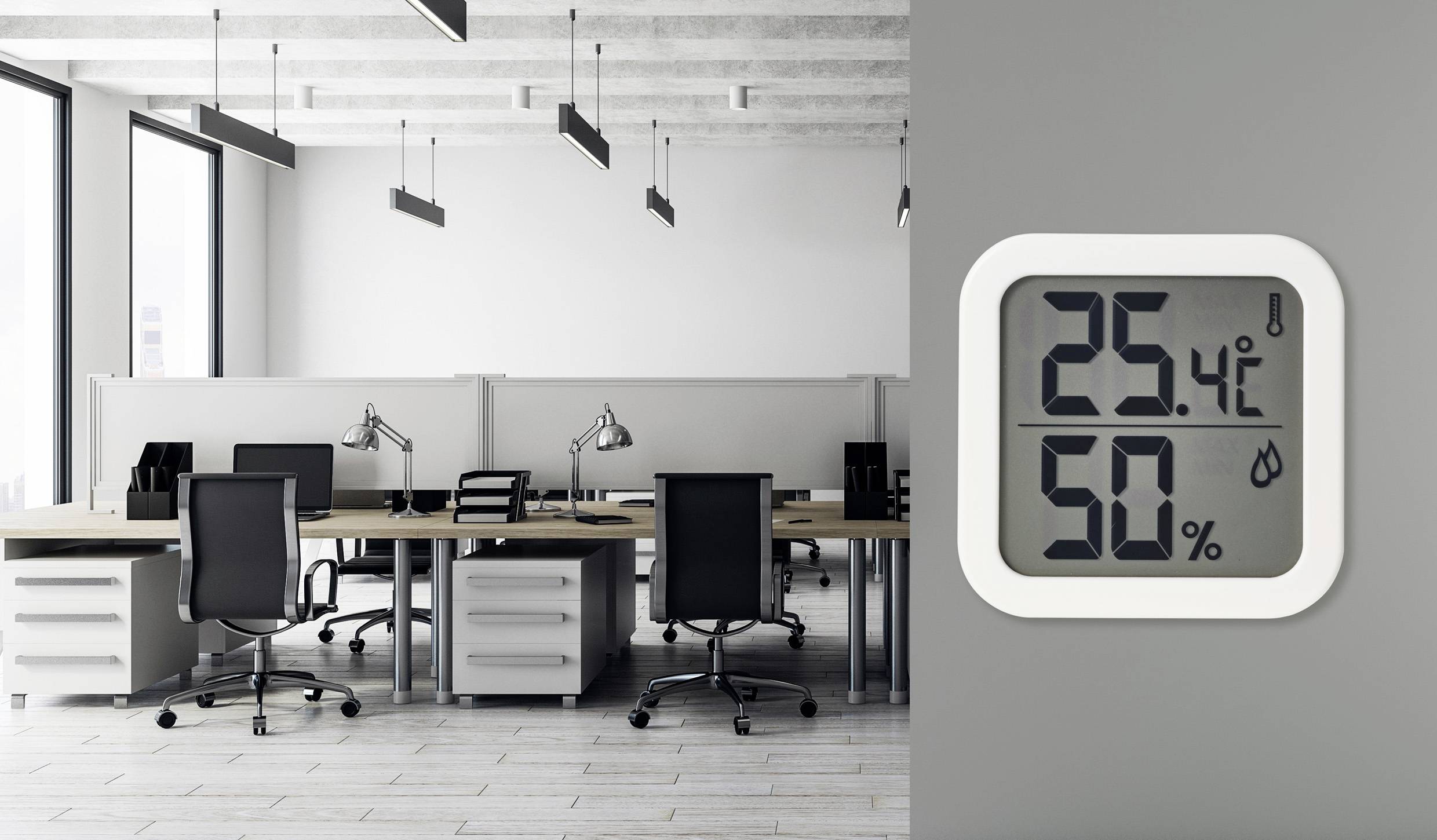 Digitální teploměr a vlhkoměr na šedé zdi ukazuje '25,4°C' a '50%' relativní vlhkosti v moderní kanceláři s psacími stoly.