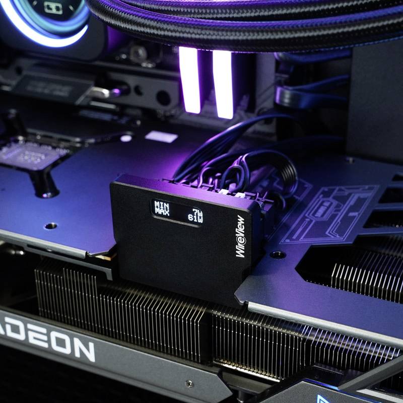 Detailní záběr počítačového hardwaru s namontovaným zařízením Wireview, které zobrazuje síťové napětí. V pozadí jsou viditelné chladicí komponenty.