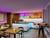 Moderní lounge s elegantním barem, neonově barevným osvětlením, dřevěnými stoly a útulnými sedacími prostory v atmosférické náladě.