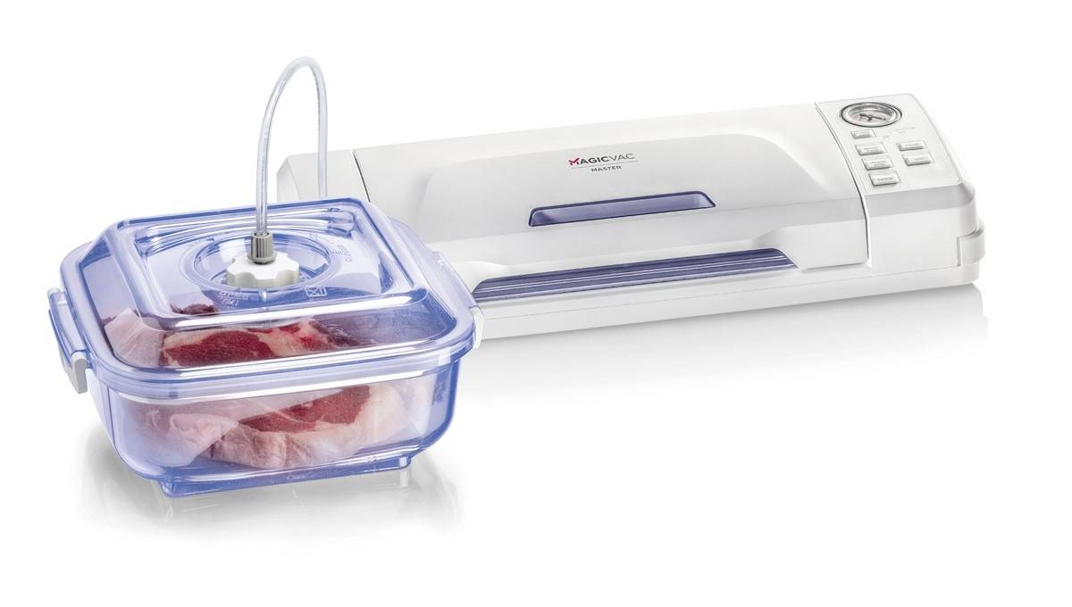 Vakuovací přístroj vedle nádoby s kusem syrového masa. Nádoba je připojena hadicí k přístroji.