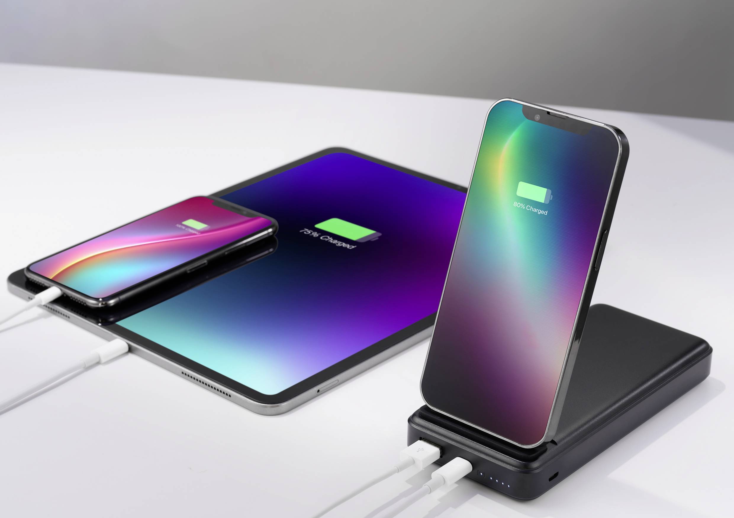 Tři mobilní zařízení (dva smartphony, jeden tablet) jsou současně nabíjeny. Na obrazovkách každého z nich je zobrazeno '80% nabito'.